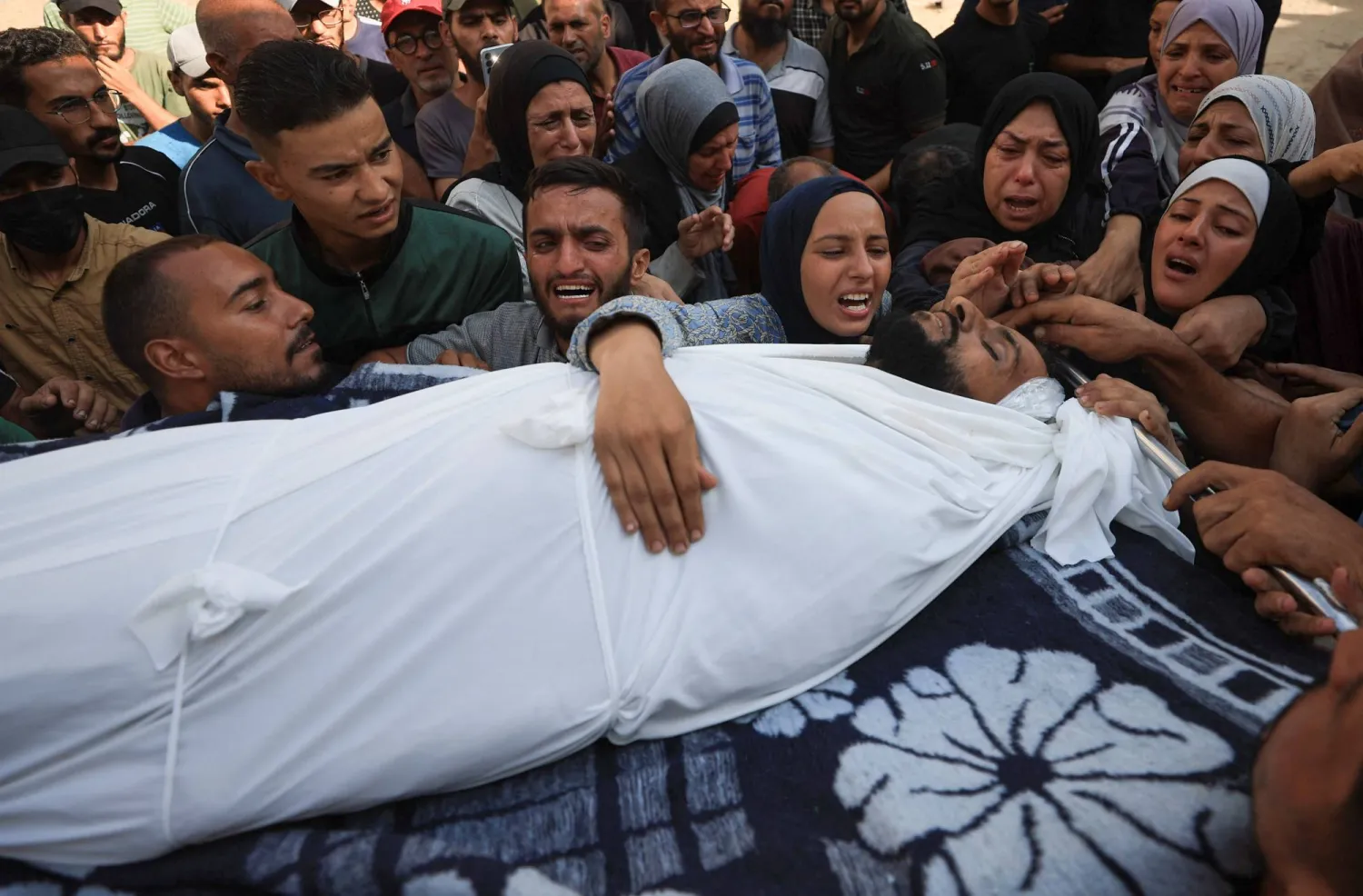 تفاعل المشيعون بالقرب من جثمان فلسطيني قُتل بنيران إسرائيلية أثناء محاولتهم تلقي المساعدات يوم الأحد (رويترز)