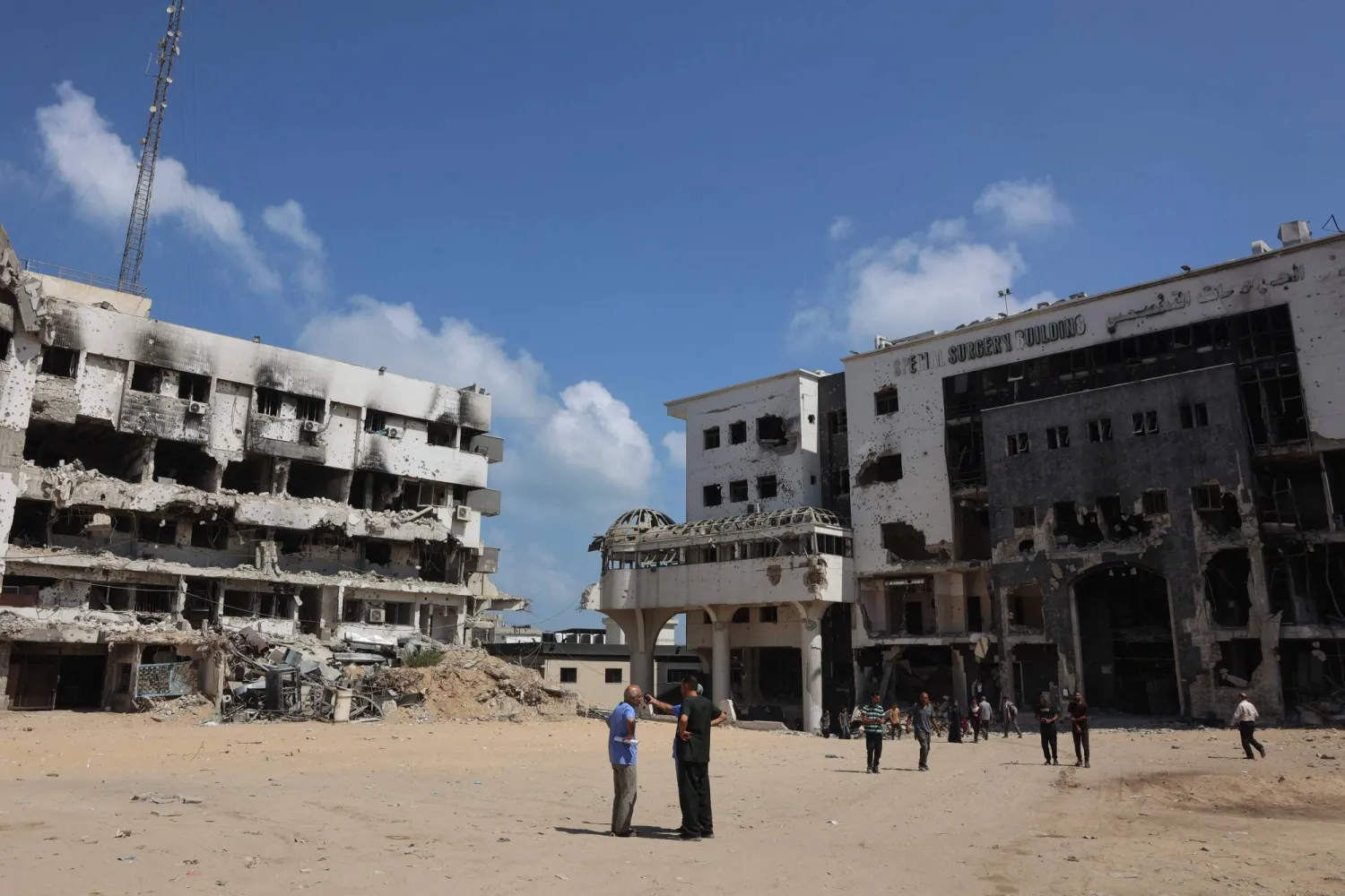 أشخاص يقفون في مجمع مستشفى «الشفاء» المدمَّر في مدينة غزة (أ.ف.ب)