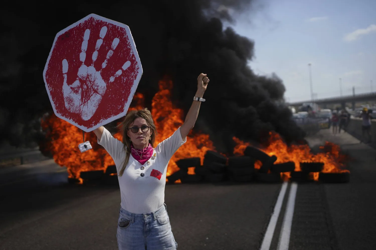 متظاهرة إسرائيلية تقطع طريقاً رئيسياً خلال مظاهرة يوم الثلاثاء تطالب بإنهاء الحرب (أ.ب)