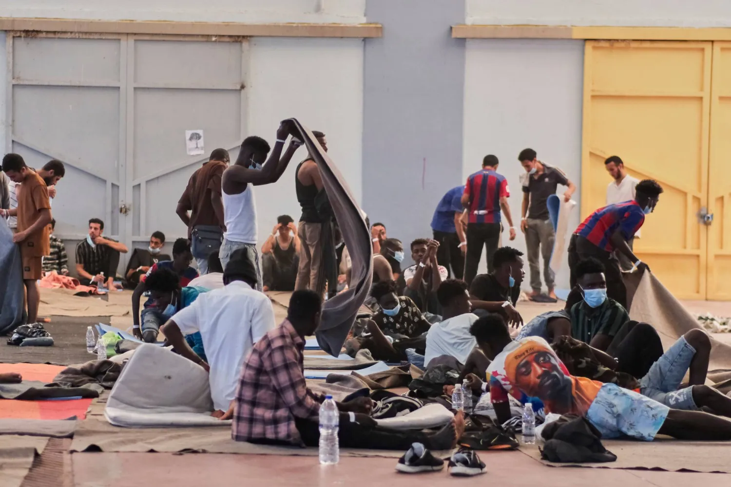 مهاجرون وصلوا مؤخراً إلى جزيرة كريت تحت الحراسة في ملجأ مؤقت في قرية أجيا في الجزيرة جنوب اليونان 19 أغسطس 2025 (أ.ب)