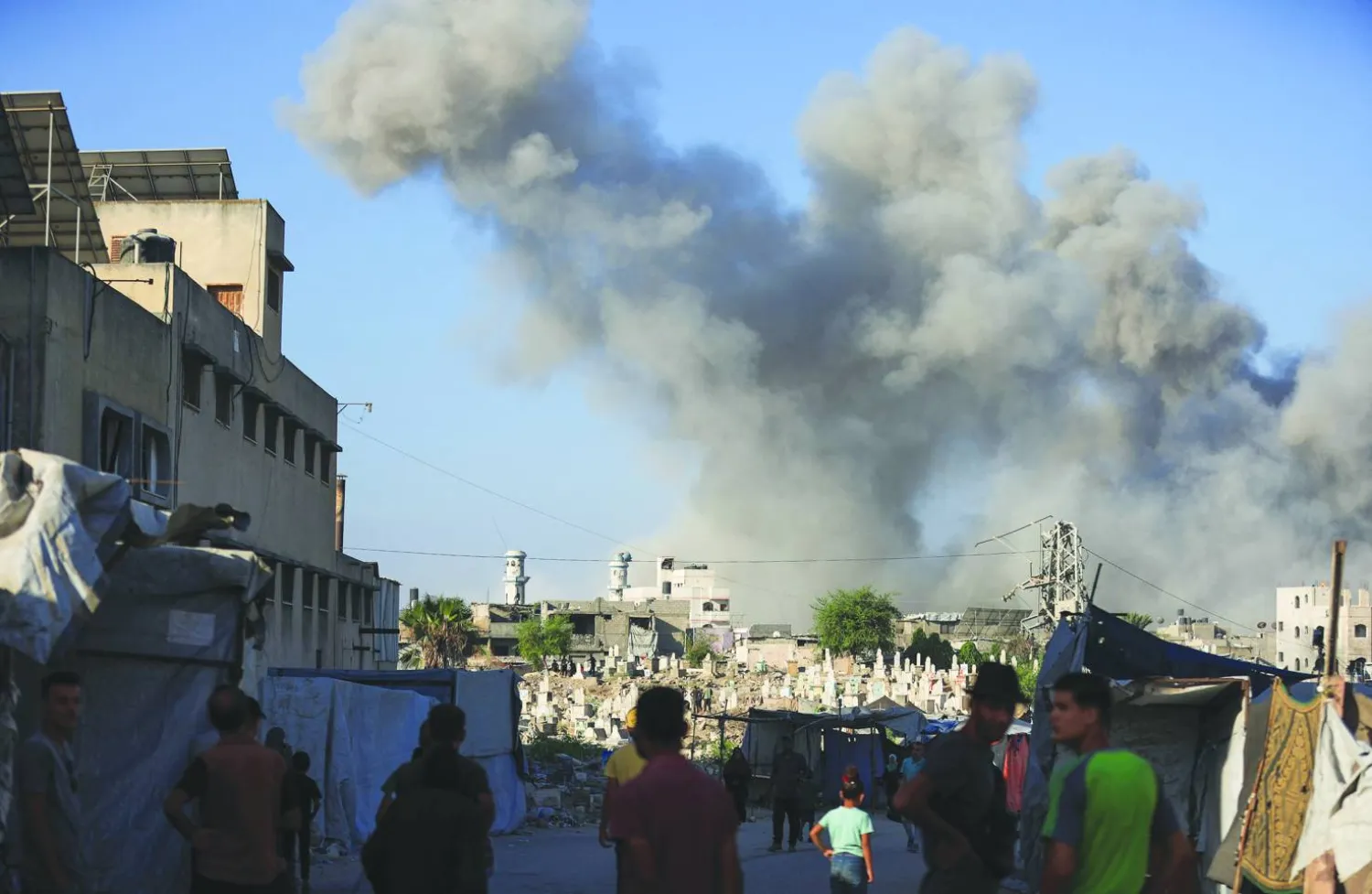 
فلسطينيون ينظرون إلى تصاعد الدخان بعد انفجار خلال عملية إسرائيلية في مدينة غزة أمس (رويترز)