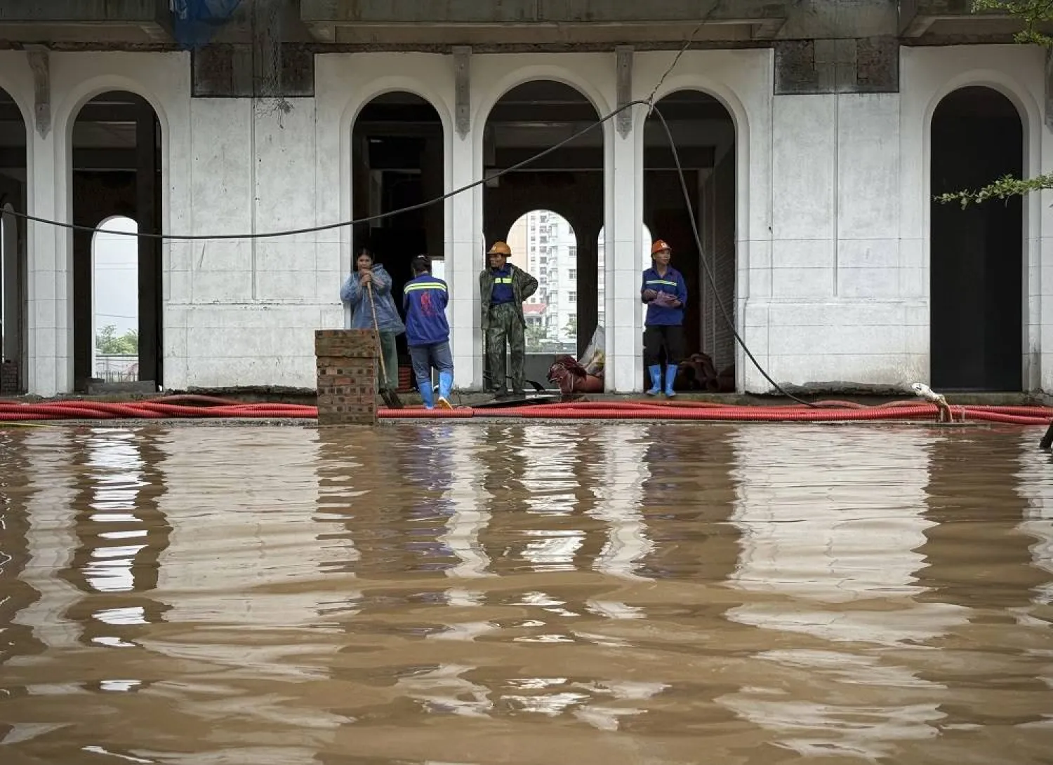 Construction workers take a break as the site is flooded in the aftermath of Typhoon Kajiki in Hanoi, Vietnam, Wednesday, Aug. 27, 2025. (AP)