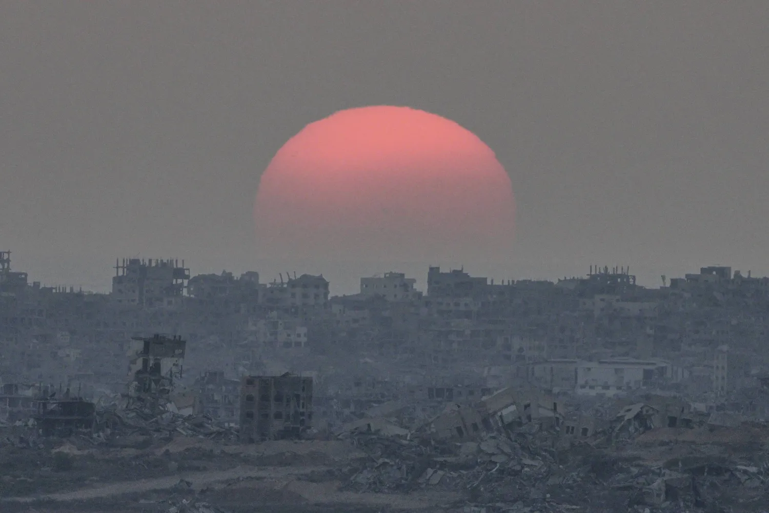 The sun sets behind buildings destroyed during Israeli ground and air operations in the Gaza Strip, as seen from southern Israel, Tuesday, Aug. 26, 2025. (AP)
