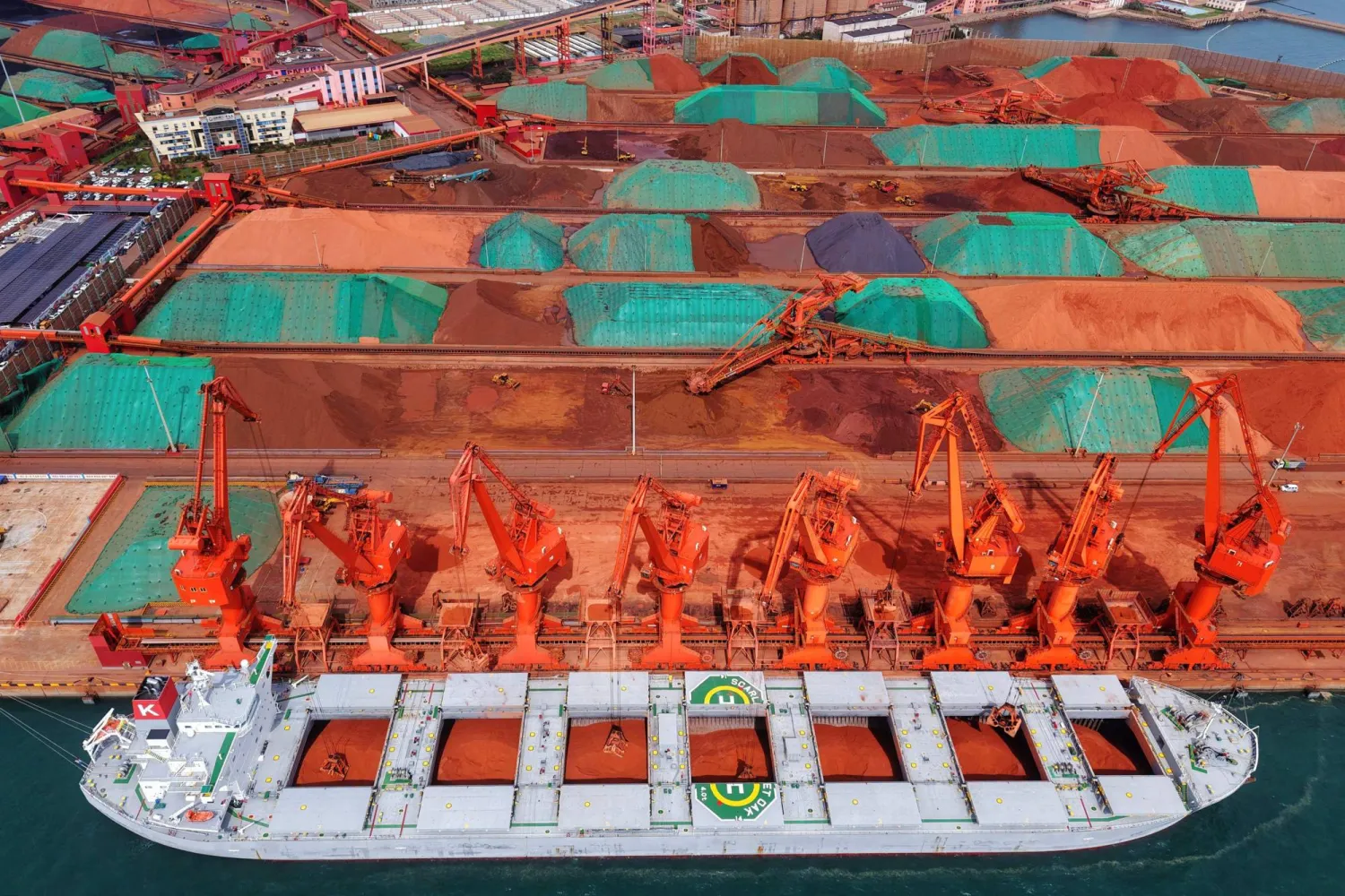 رافعات تقوم بتحميل خام الحديد المستورد من ناقلة بحرية في ميناء قينغداو شرق الصين (أ.ف.ب)