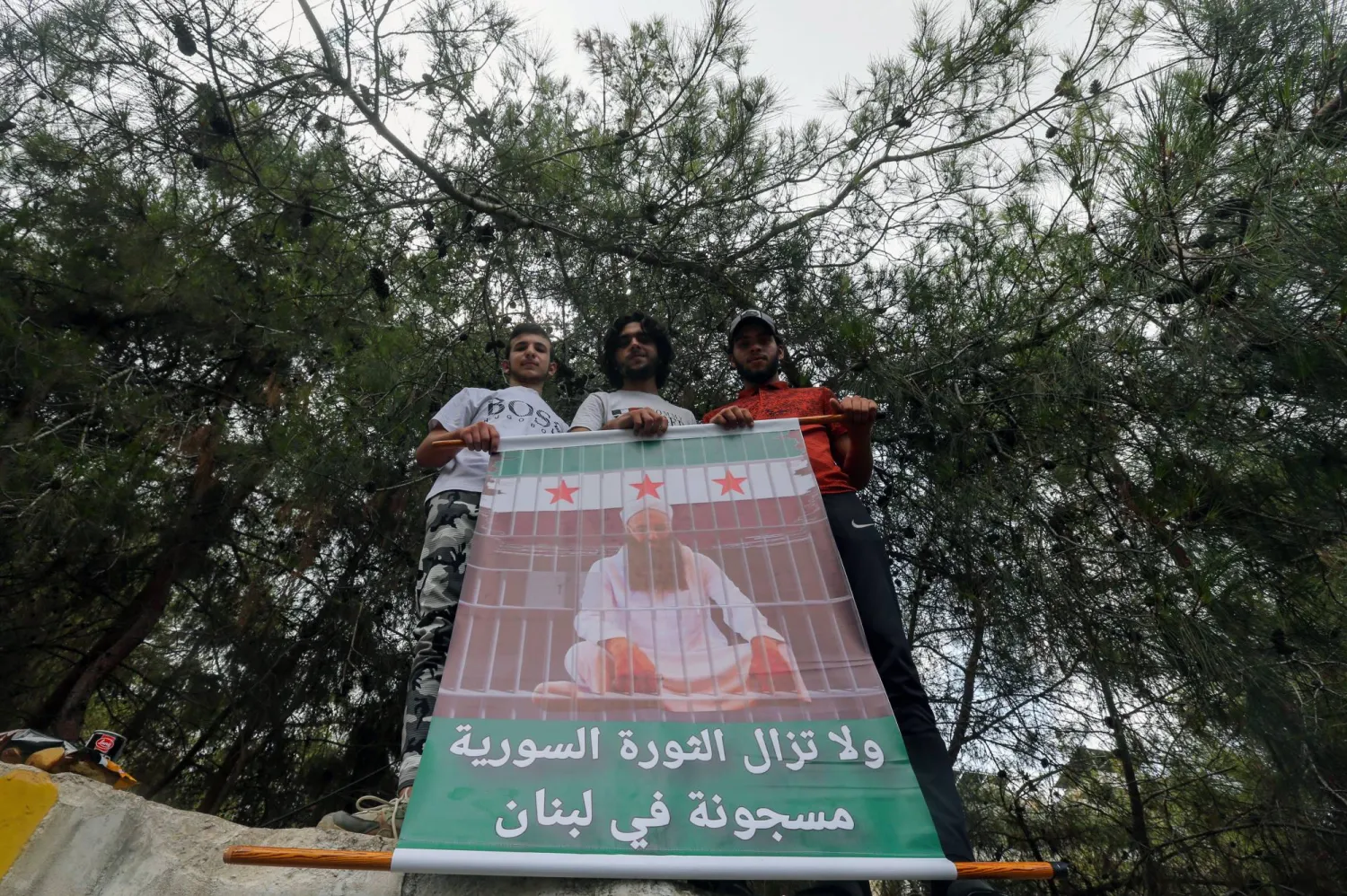 شباب يحملون صورة الشيخ المتشدد أحمد الأسير المعروف بمواقفه ضد «حزب الله» والمحكوم بالسجن على خلفية الاشتباك مع عناصر الجيش في صيدا عام 2013، وكتب على الصورة «لا تزال الثورة السورية مسجونة في لبنان» (إ.ب.أ)