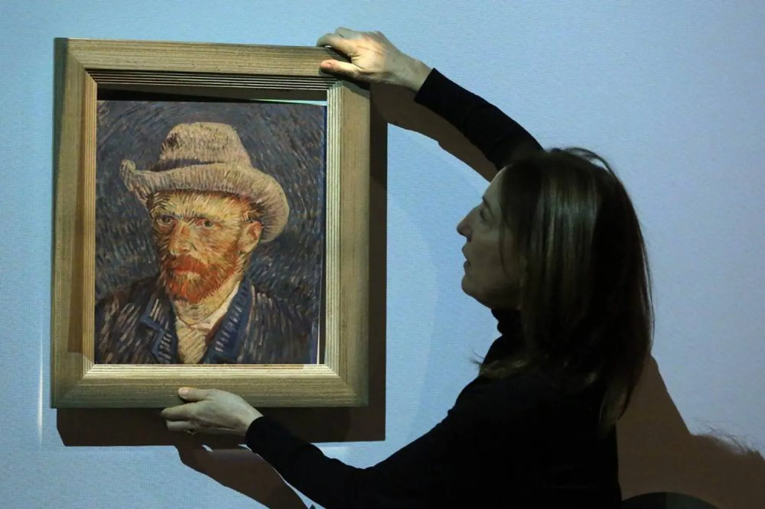 Emilie Gordenker, director of the Van Gogh Museum, removes the frame of a reproduction of the painting "Self-Portrait with Grey Felt Hat" by Vincent Van Gogh as part of an interactive section of the exhibition "Choosing Vincent - Portrait of a family history" at Van Gogh Museum in Amsterdam, on February 8, 2023. (Valeria Mongelli / AFP) 