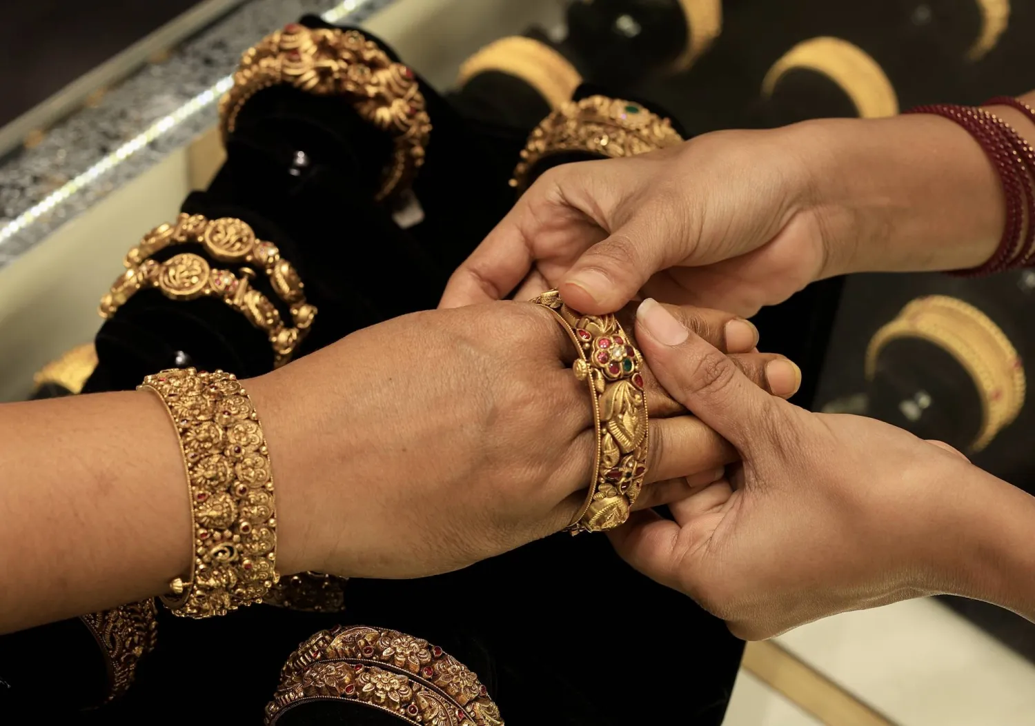 امرأة هندية تُجرّب حُلياً ذهبية في متجر مجوهرات في بنغالور بالهند (إ.ب.أ)
