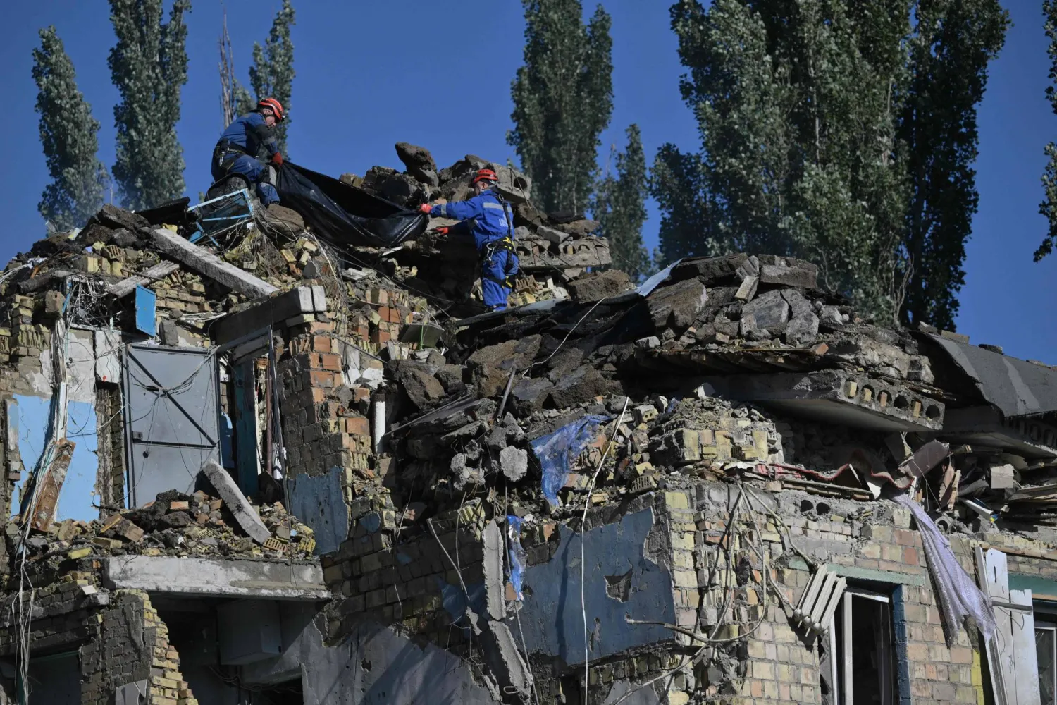 يحمل رجال الإنقاذ الأوكرانيون جثة ضحية انتشلت خلال عملية بحث وإنقاذ في موقع مبنى سكني تضرر بشدة جراء هجوم صاروخي روسي في كييف (أ.ف.ب)