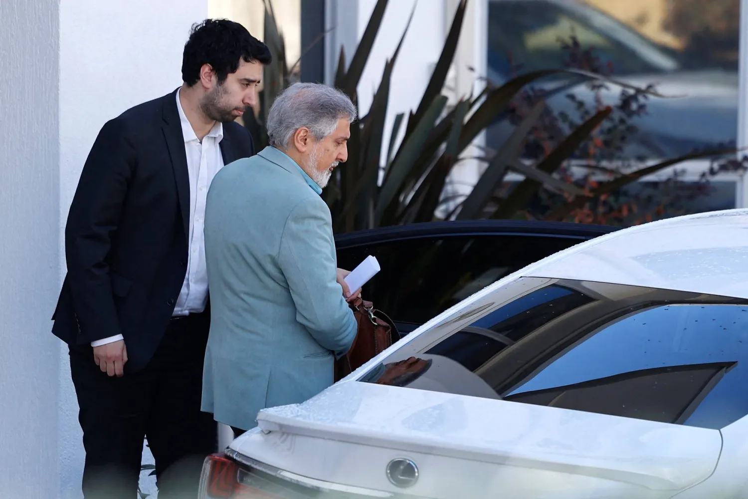 السفير الإيراني لدى أستراليا أحمد صادقي (يمين) يسير نحو سيارته داخل حرم سفارة بلاده في كانبرا... 27 أغسطس 2025 (أ.ف.ب)