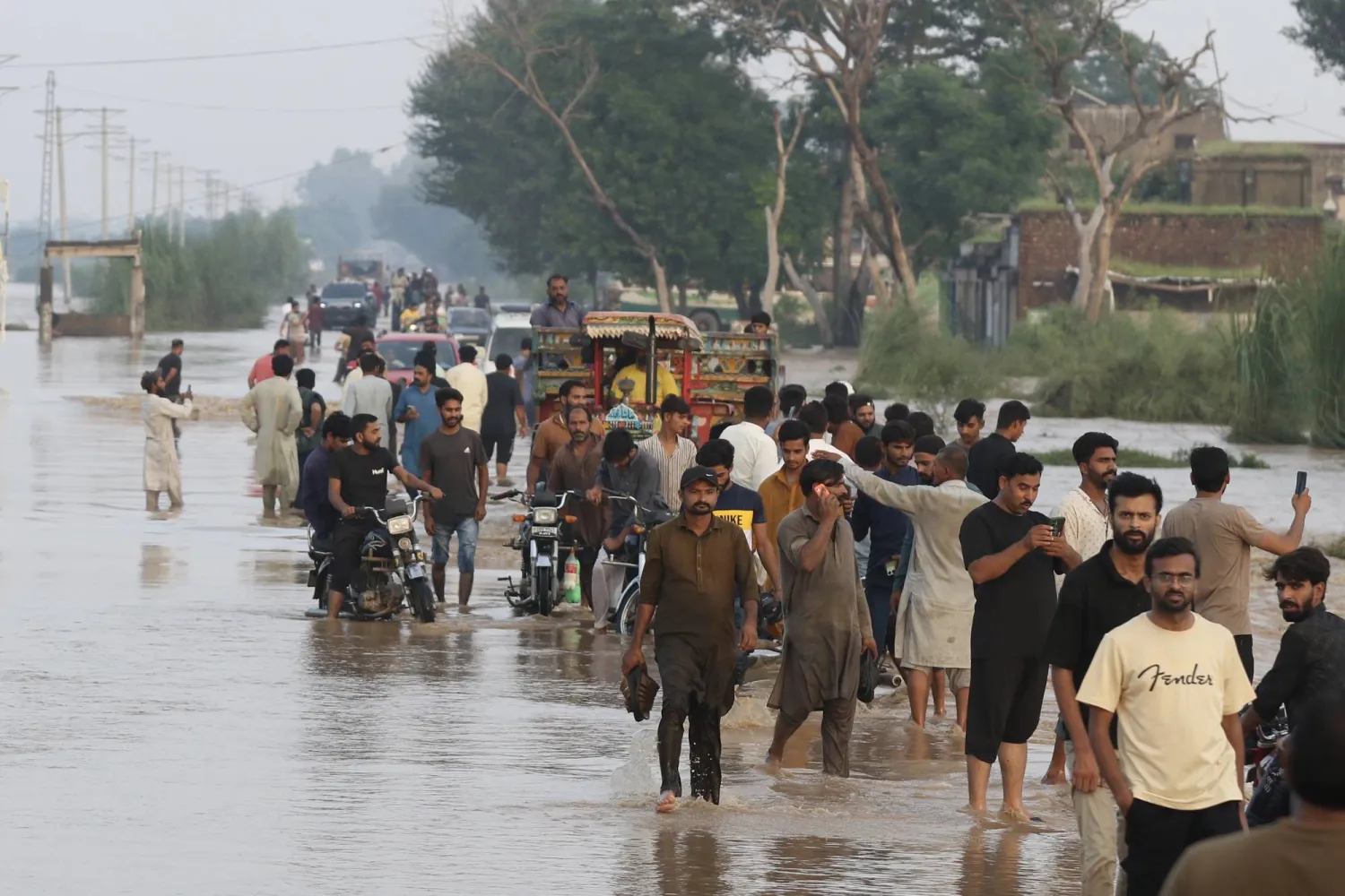 People wade through a flooded road after rising floodwaters in river Ravi, in Narowal, Punjab province, Lahore, Pakistan, 27 August 2025. EPA/RAHAT DAR