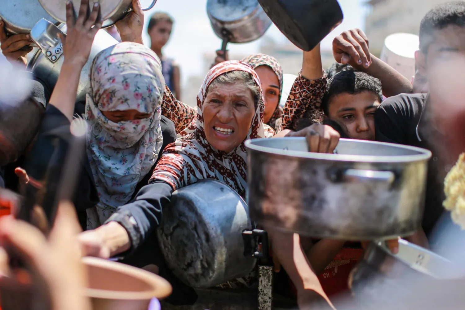 People try to get rice from a charity kitchen providing food for free in the west of Gaza City, on August 28, 2025, as the war between Israel and the Hamas movement continues. (Photo by BASHAR TALEB / AFP)