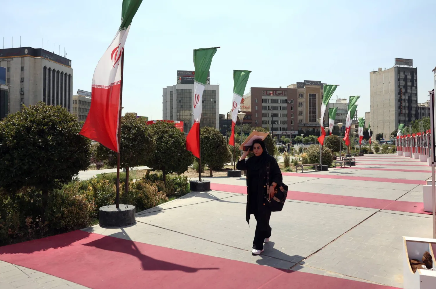 Iranians walk next to Iran’s national flags in a street in Tehran, Iran, 28 August 2025. EPA/ABEDIN TAHERKENAREH