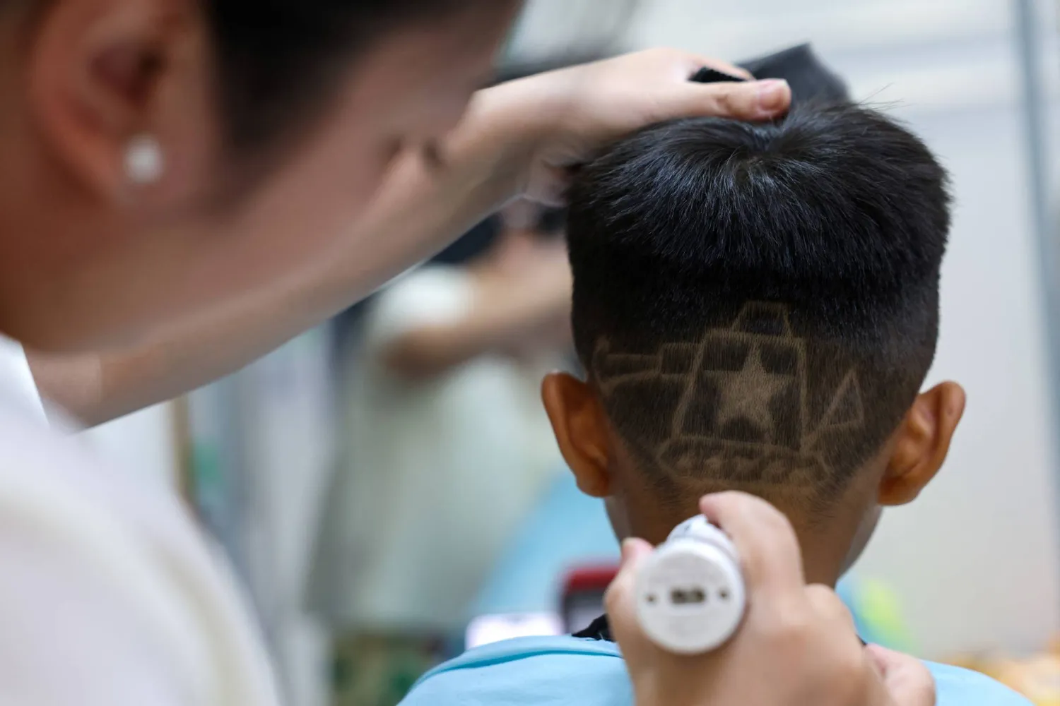 Hair salon owner Wang Xueru gives a child a haircut in a design of a tank to commemorate the 80th anniversary of the end of World War Two, at her store in Beijing, China August 28, 2025. REUTERS/Tingshu Wang