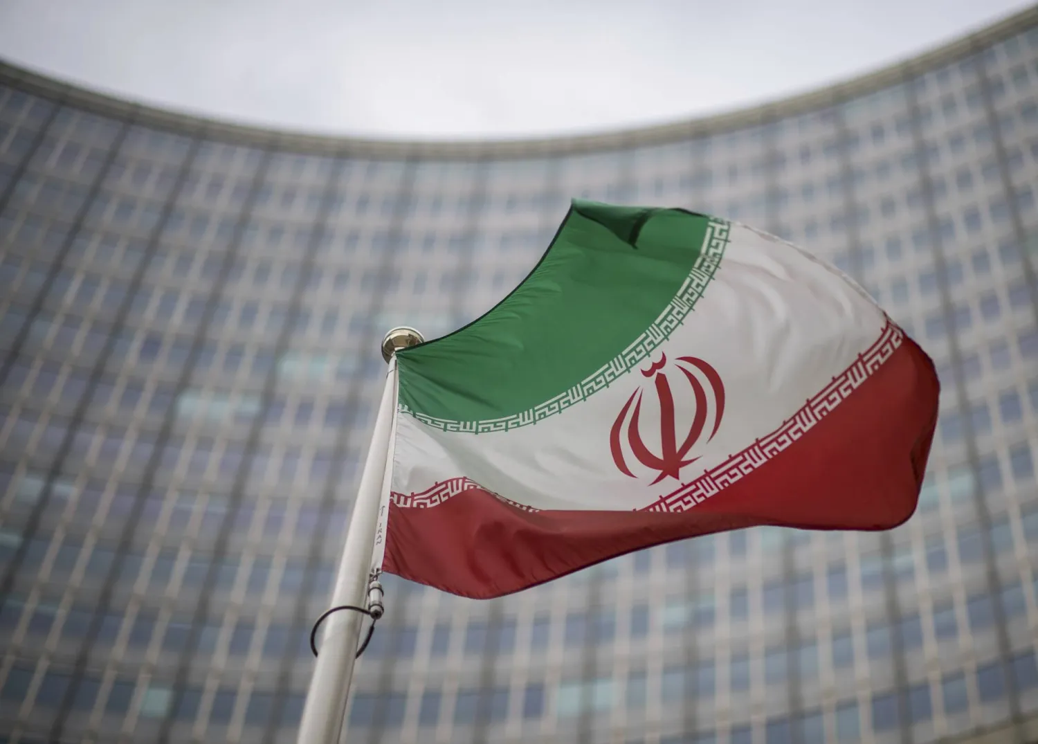 File - A national flag of Iran waves in front of the building of the International Atomic Energy Agency, IAEA, in Vienna, Austria, Friday, Dec. 17, 2021. (AP Photo/Michael Gruber, File)