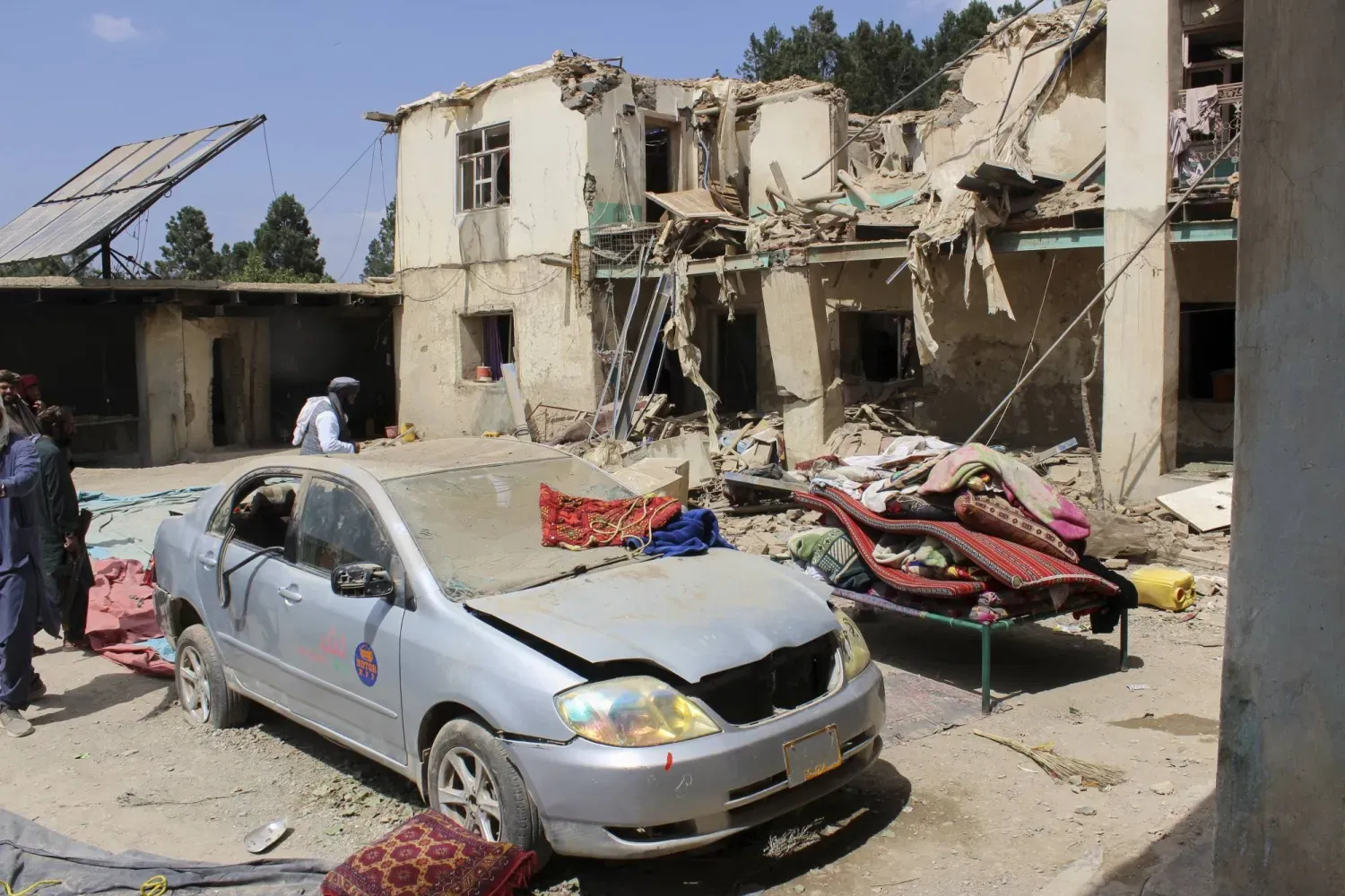 Taliban yetkililerinin, Afganistan'ın Host ilinin Spira ilçesinde Pakistan tarafından düzenlenen ölümcül İHA saldırısı olduğunu söylediği olayda yıkılan binanın bulunduğu alanı inceleyen bölge sakinleri (AP)