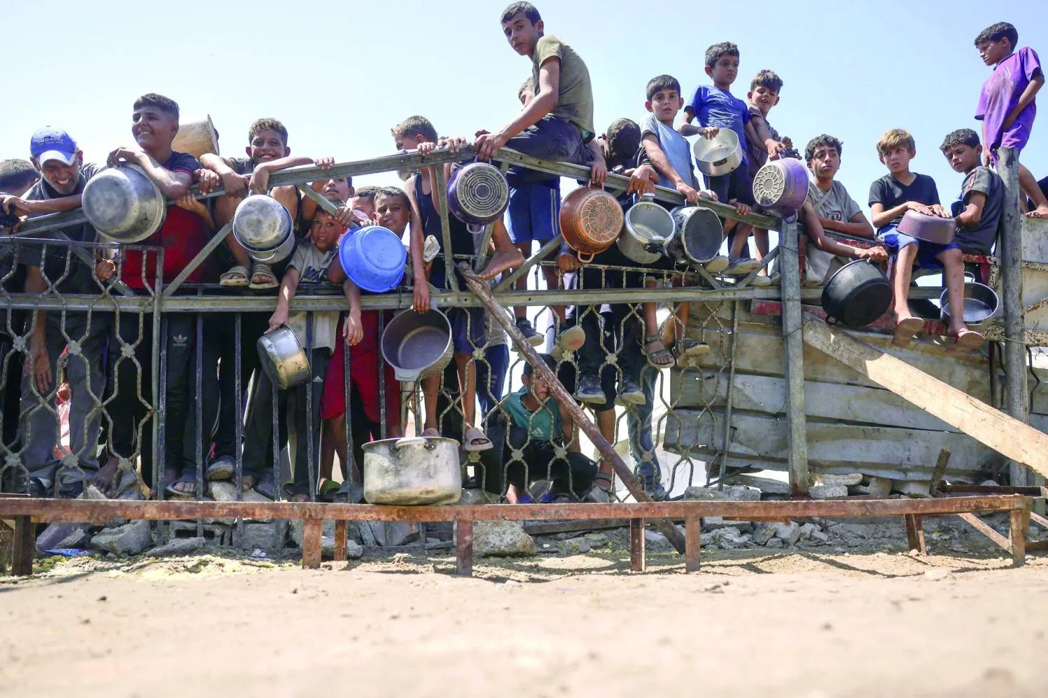 Children gather by a fence as they try to get rice from a charity kitchen providing food for free in the west of Gaza City, on August 28, 2025, as the war between Israel and the Hamas movement continues. (Photo by BASHAR TALEB / AFP)