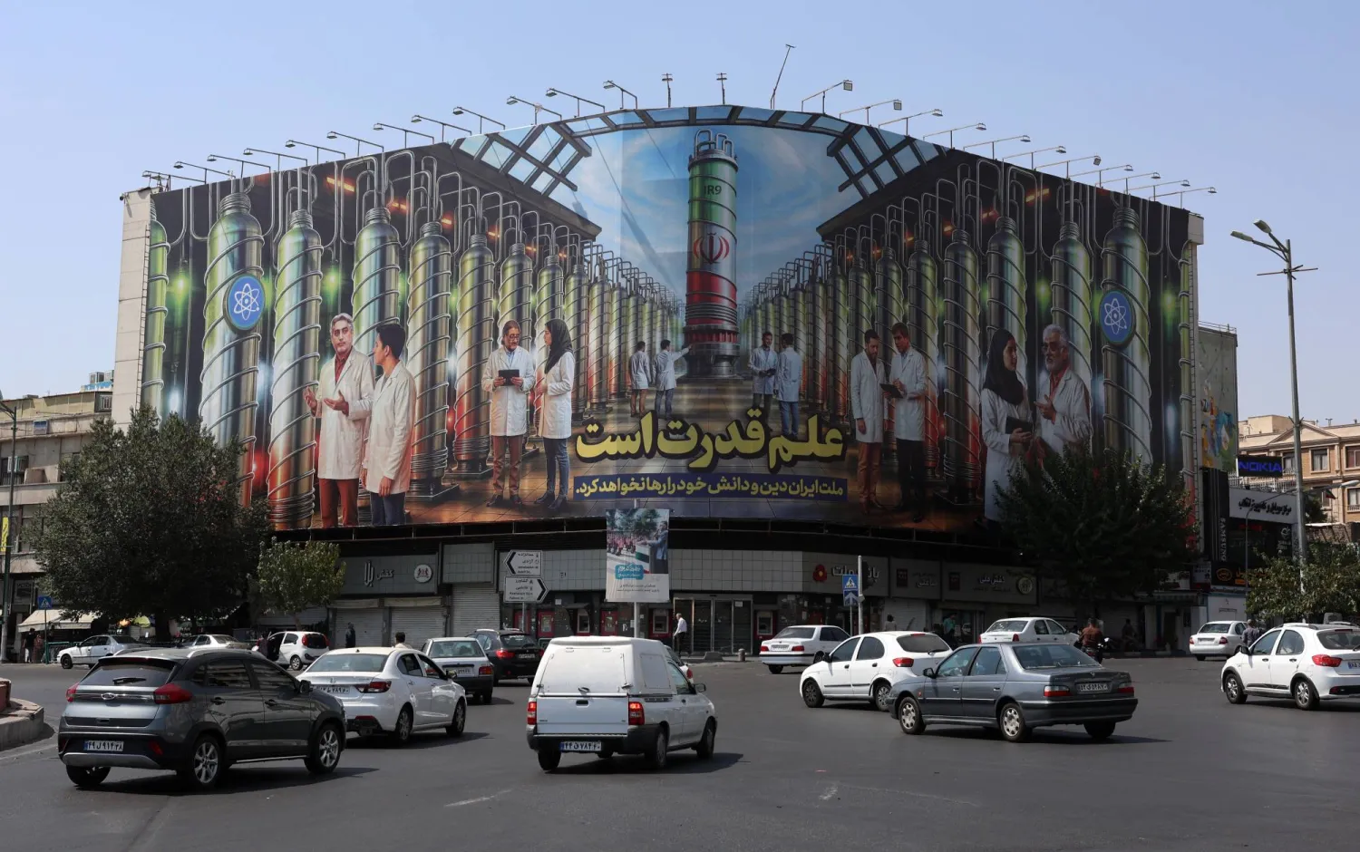 ميدان انقلاب في طهران وتظهر في الصورة المأخوذة الجمعة لوحة إعلانية تبين أجهزة طرد مركزي نووية وجملة باللغة الفارسية تقول «العلم هو القوة» (إ.ب.أ)