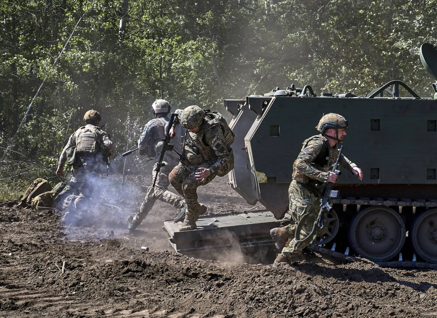 جنود أوكرانيون من الحرس الوطني يخرجون من مدرعة أميركية طراز M113 خلال تدريبات بمنطقة خاركيف (إ.ب.أ)