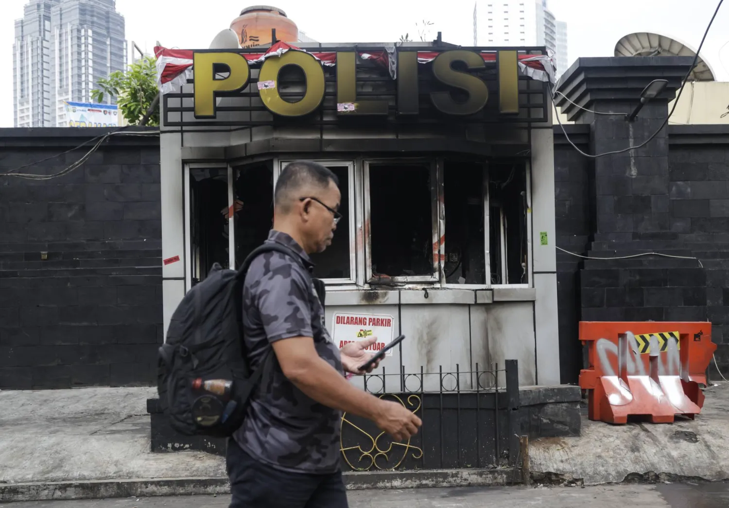 رجل إندونيسي يمر أمام نقطة شرطة محترقة في العاصمة الإندونيسية جاكارتا (إ.ب.أ)