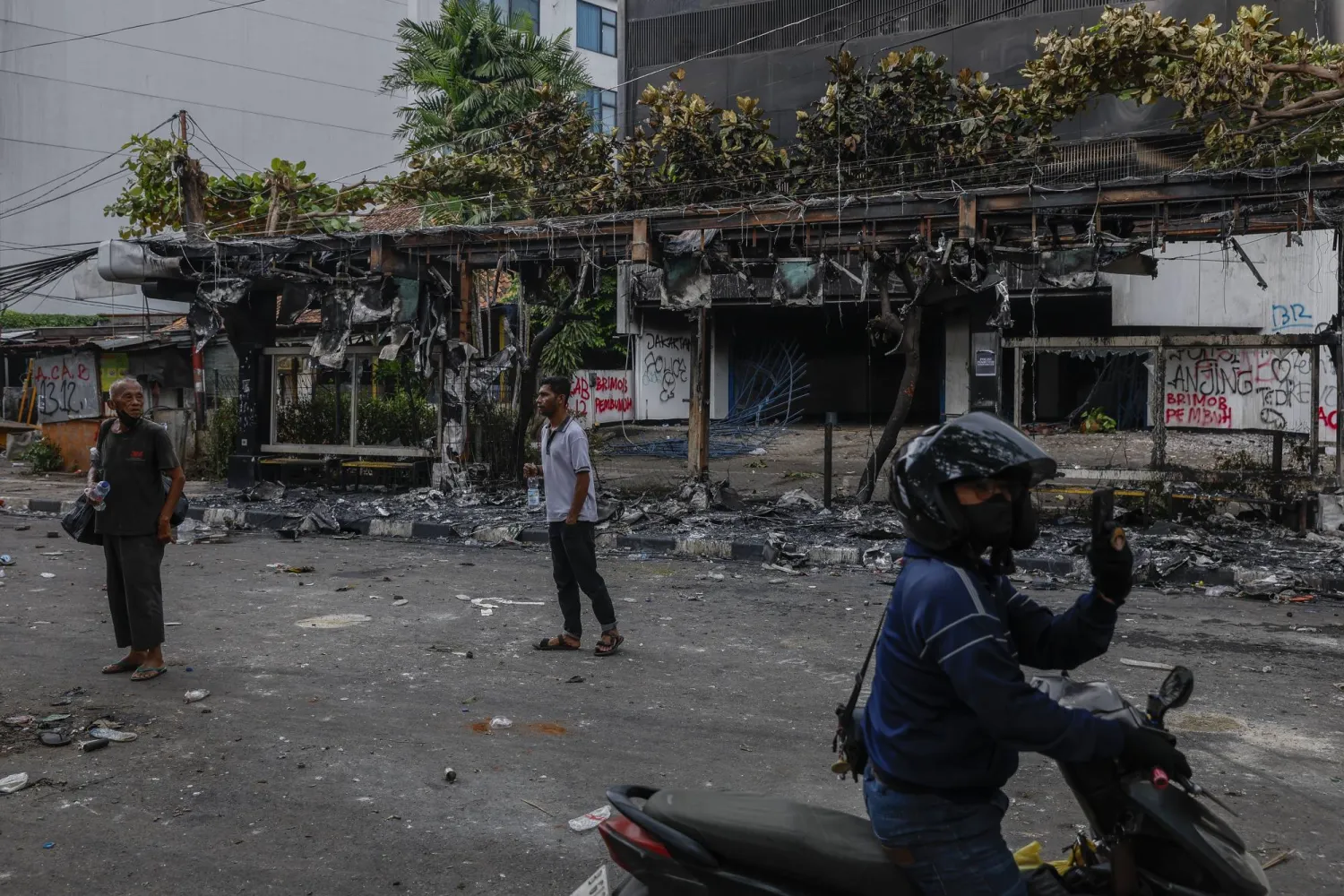 People inspect the area in front of a burnt bus stop set on fire during a protest outside the Mobile Brigade police headquarter in Jakarta, Indonesia, 30 August 2025. EPA/MAST IRHAM