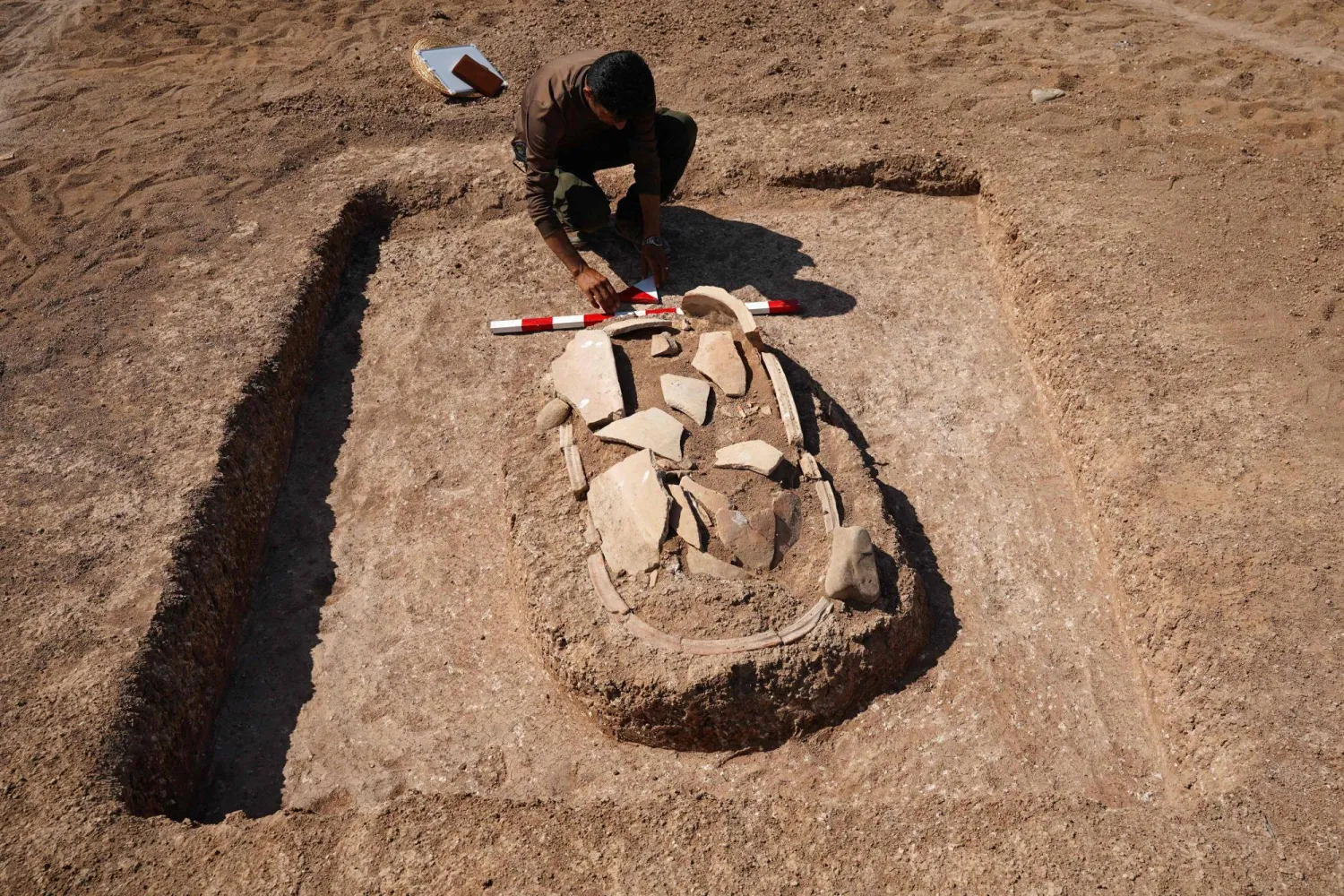 A Kurdish member of the Dohuk Antiquities Department works on a grave unearthed on the banks of Mosul Dam on an archaeological site in the Khanke sub-district of Duhok Governorate on August 30, 2025. (Photo by Ismael ADNAN / AFP)