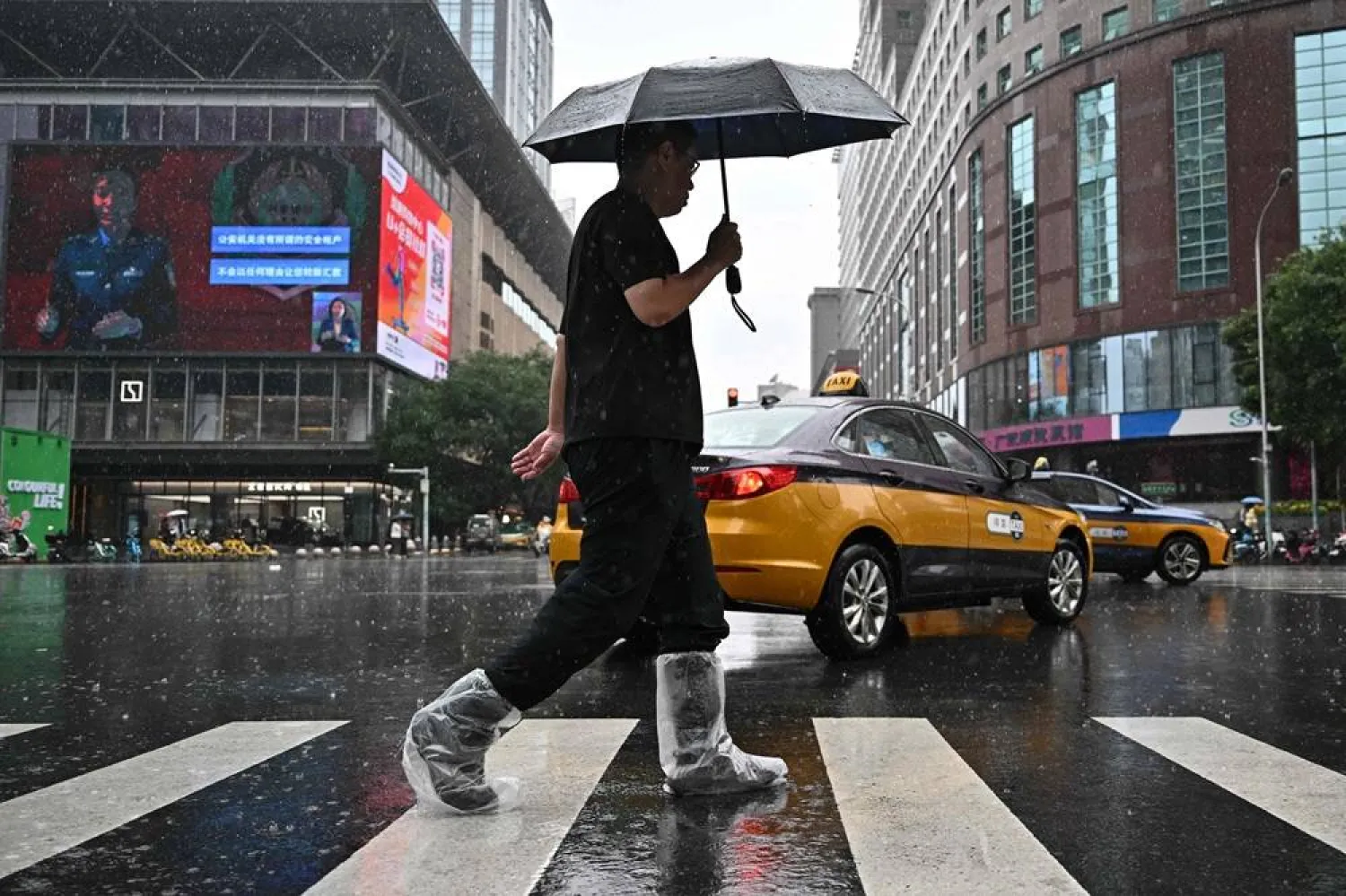 A man uses an umbrella to protect himself from the rain in Beijing on August 27, 2025. (AFP)