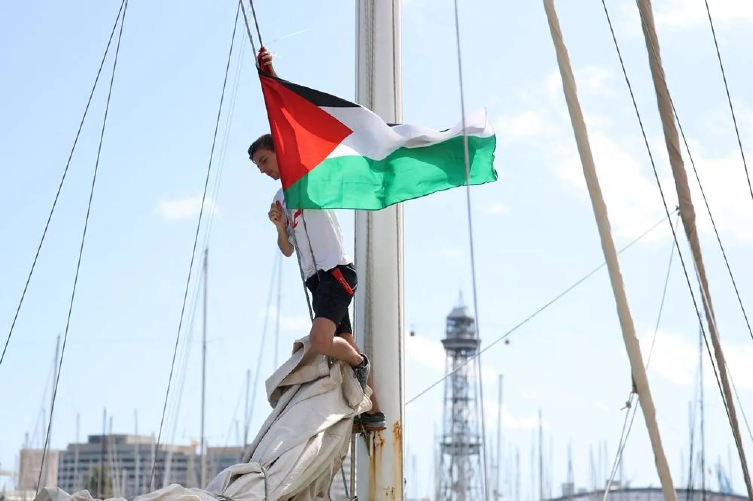 A member of the Freedom Flotilla places a Palestinian flag on one of the boats of a flotilla carrying humanitarian aid and activists preparing to leave for Gaza, in Barcelona on August 30, 2025. (AFP)