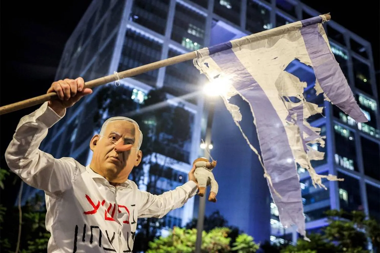 A demonstrator wearing a mask depicting Israeli Prime Minister Benjamin Netanyahu with an elongated nose, evoking the literary character Pinocchio, poses during an anti-government protest organized by the families of the Israeli hostages taken captive in the Gaza Strip since the October 2023 calling for action to secure their release and a ceasefire in the war against Hamas, outside the Defense Ministry headquarters in Tel Aviv, on August 23, 2025. (AFP)