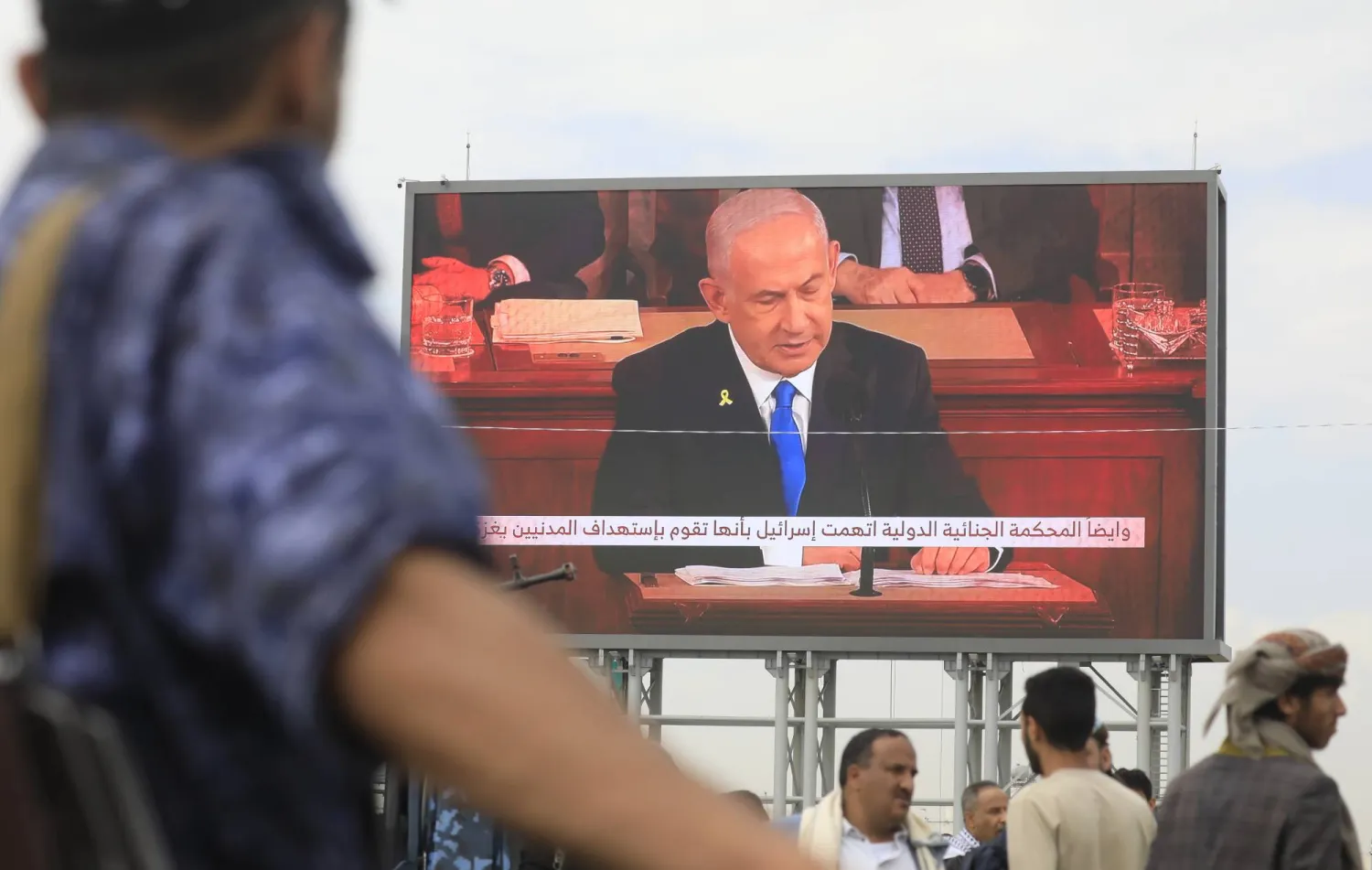 أنصار جماعة الحوثي أمام لوحة إعلانة رقمية تظهر صورة رئيس الوزراء الإسرائيلي بنيامين نتنياهو خلال تظاهرات ضد الضربات الإسرائيلية في صنعاء (إ.ب.أ)