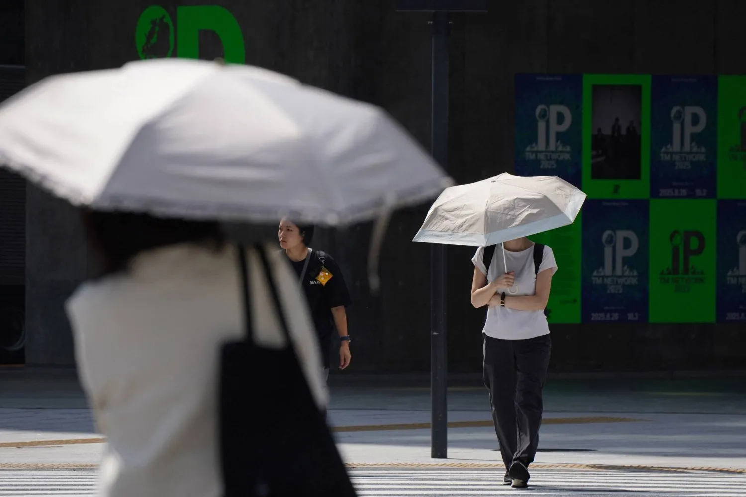 People with umbrellas walk in the scorching sun in Tokyo on September 1, 2025. (Photo by Kazuhiro NOGI / AFP)