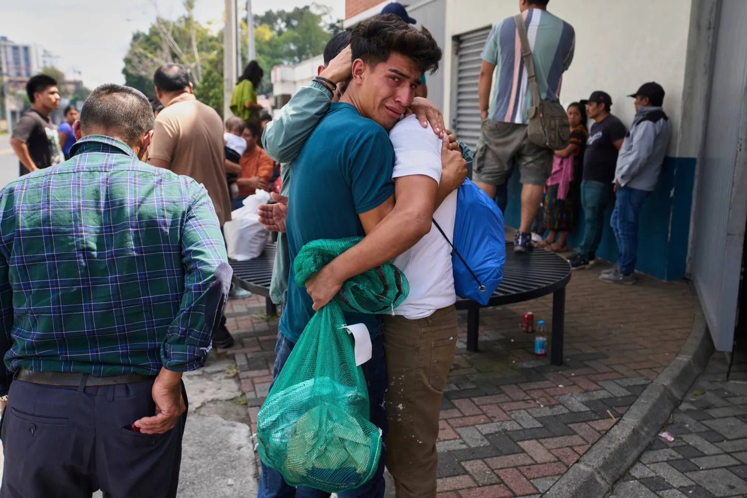 غواتيمالي يحتضنه قريبه بعد ترحيله من الولايات المتحدة خارج مطار لا أورورا الدولي في غواتيمالا العاصمة (أ.ب)