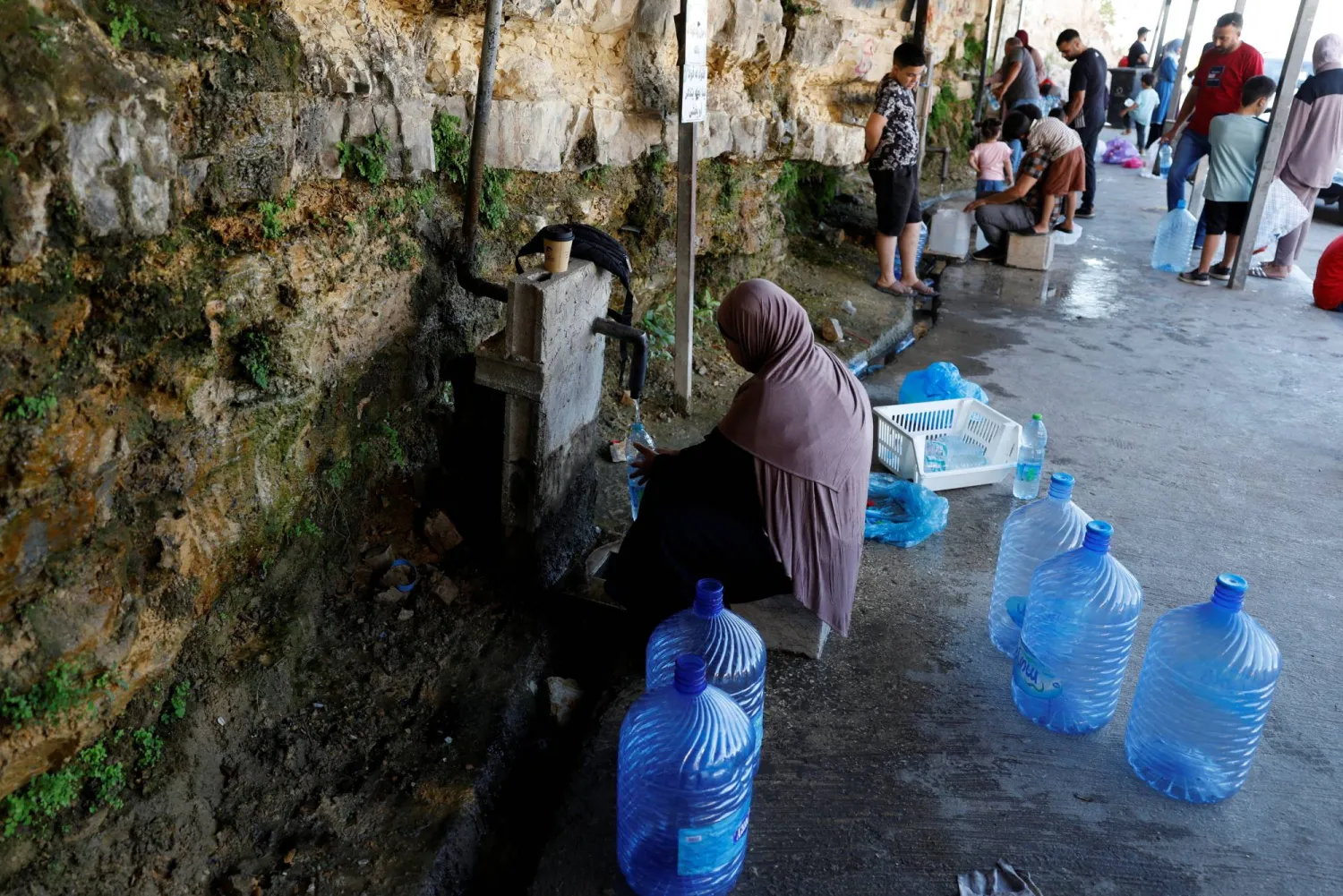 امرأة فلسطينية تملأ حاويات المياه من نقطة مياه عامة في رام الله بالضفة الغربية المحتلة (رويترز)