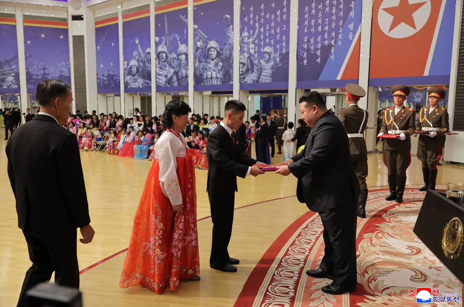  كيم يسلم صورة ملفوفة بالعلم الكوري الشمالي لعائلة جندي شارك في العمليات العسكرية الخارجية في بيونغ يانغ (أ.ف.ب)