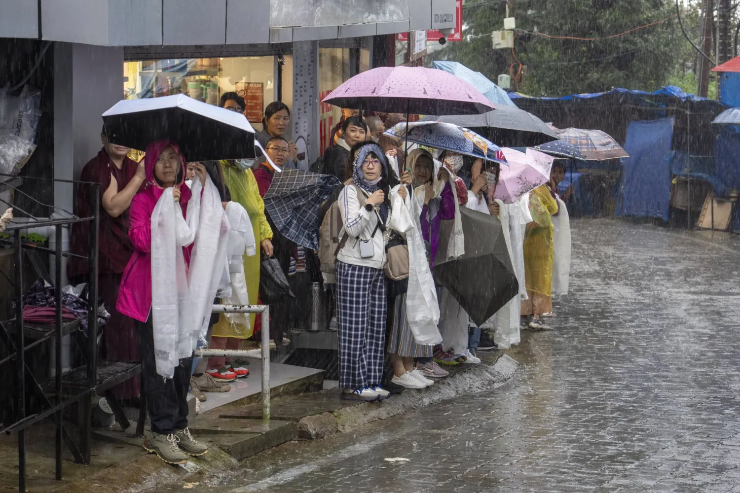 أشخاص يقفون تحت مياه الأمطار في شوارع الهند (أ.ب)