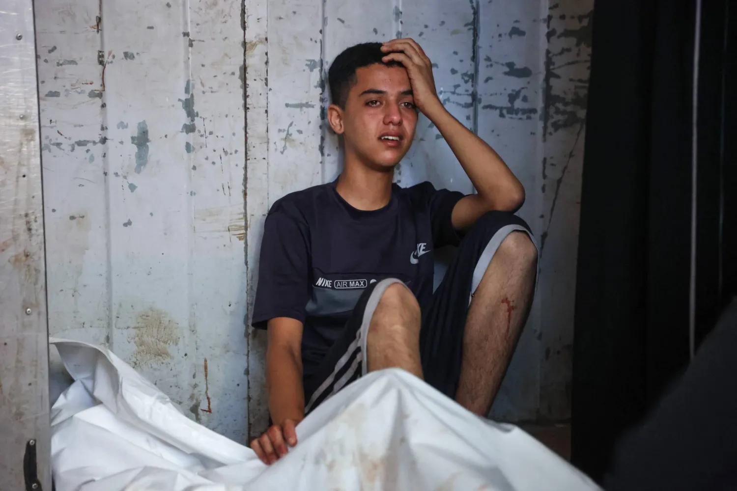فتى فلسطيني يبكي بجوار جثمان قُتل صاحبه في ضربات بمدينة غزة فجر الثلاثاء (أ.ف.ب)