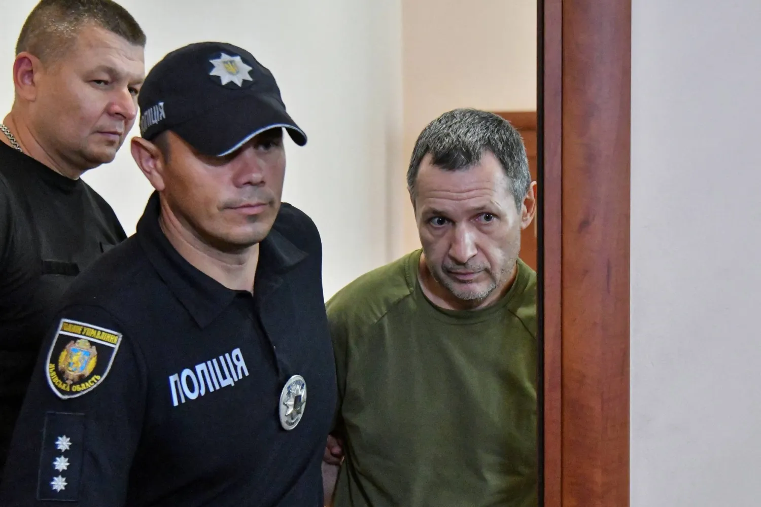 عناصر من الشرطة يرافقون ميخايلو ستسلنيكوف المشتبه به في جريمة قتل رئيس البرلمان الأوكراني السابق أندريه باروبي إلى قاعة المحكمة (رويترز)