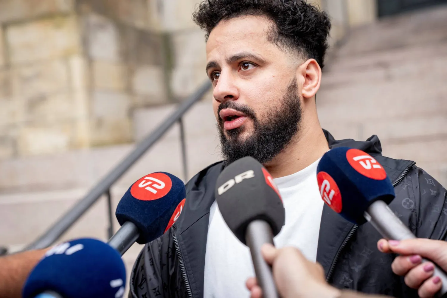 المواطن الدنماركي من أصل سوري أحمد سمسم يتحدث إلى وسائل الإعلام (رويترز)