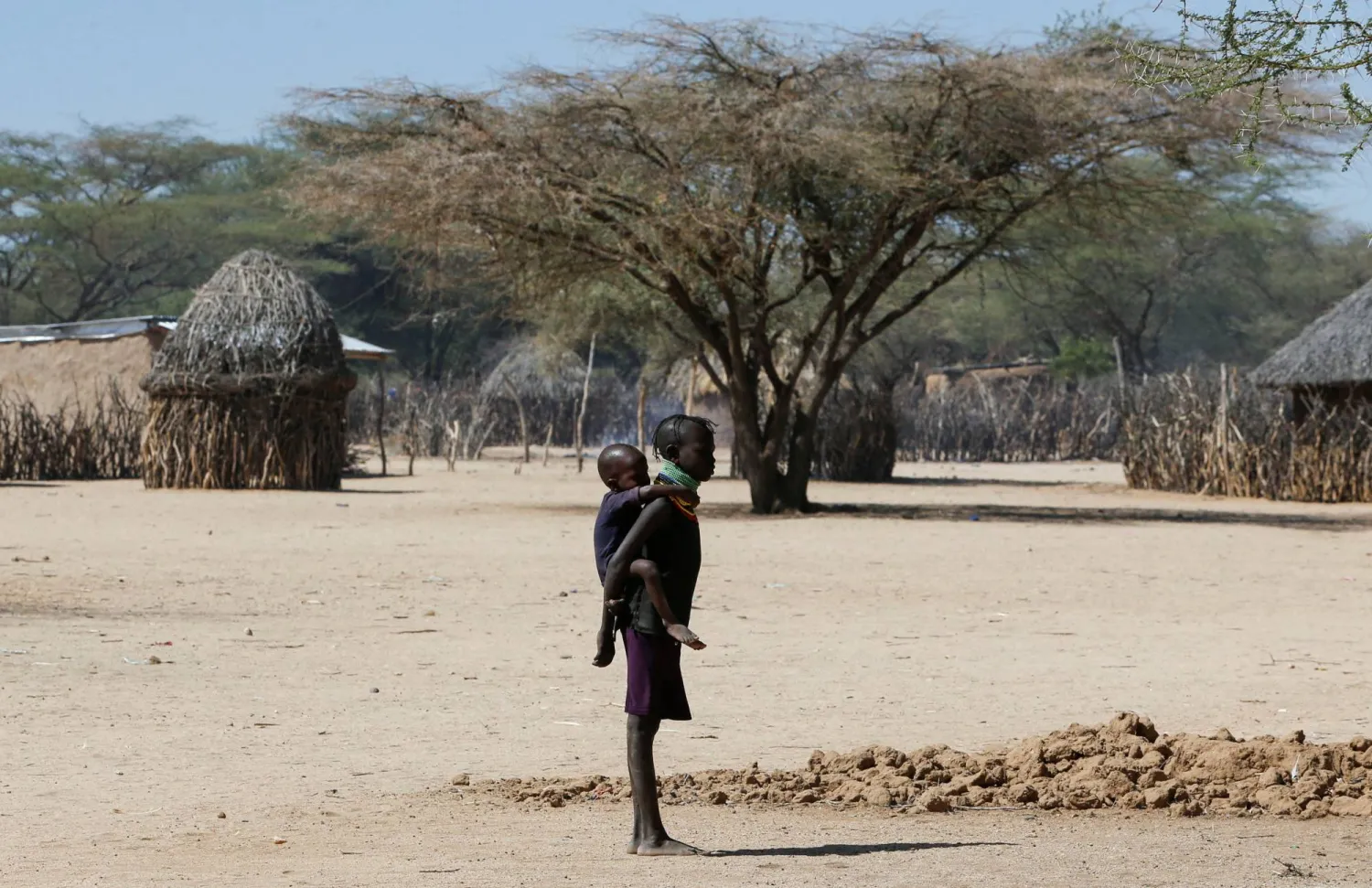 FILE PHOTO: A child affected by the worsening drought due to failed monsoon seasons, carries her sibling as they stand near their makeshift shelter within Sopel village in Turkana, Kenya September 27, 2022. REUTERS/Thomas Mukoya/File Photo