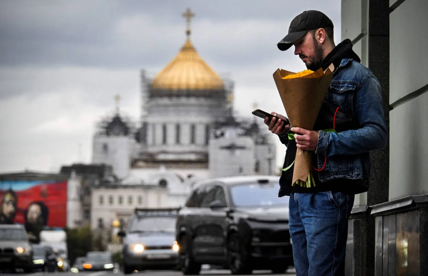 رجل يحمل الزهور أمام كاتدرائية بوسط مدينة موسكو (أ.ف.ب)