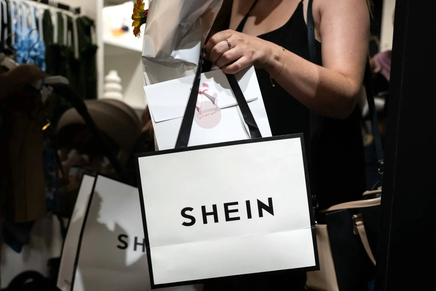 (FILES) A customer holds her bags as she leaves a pop-up store of the Chinese fast fashion brand Shein, in Dijon on June 26, 2025. (Photo by ARNAUD FINISTRE / AFP)