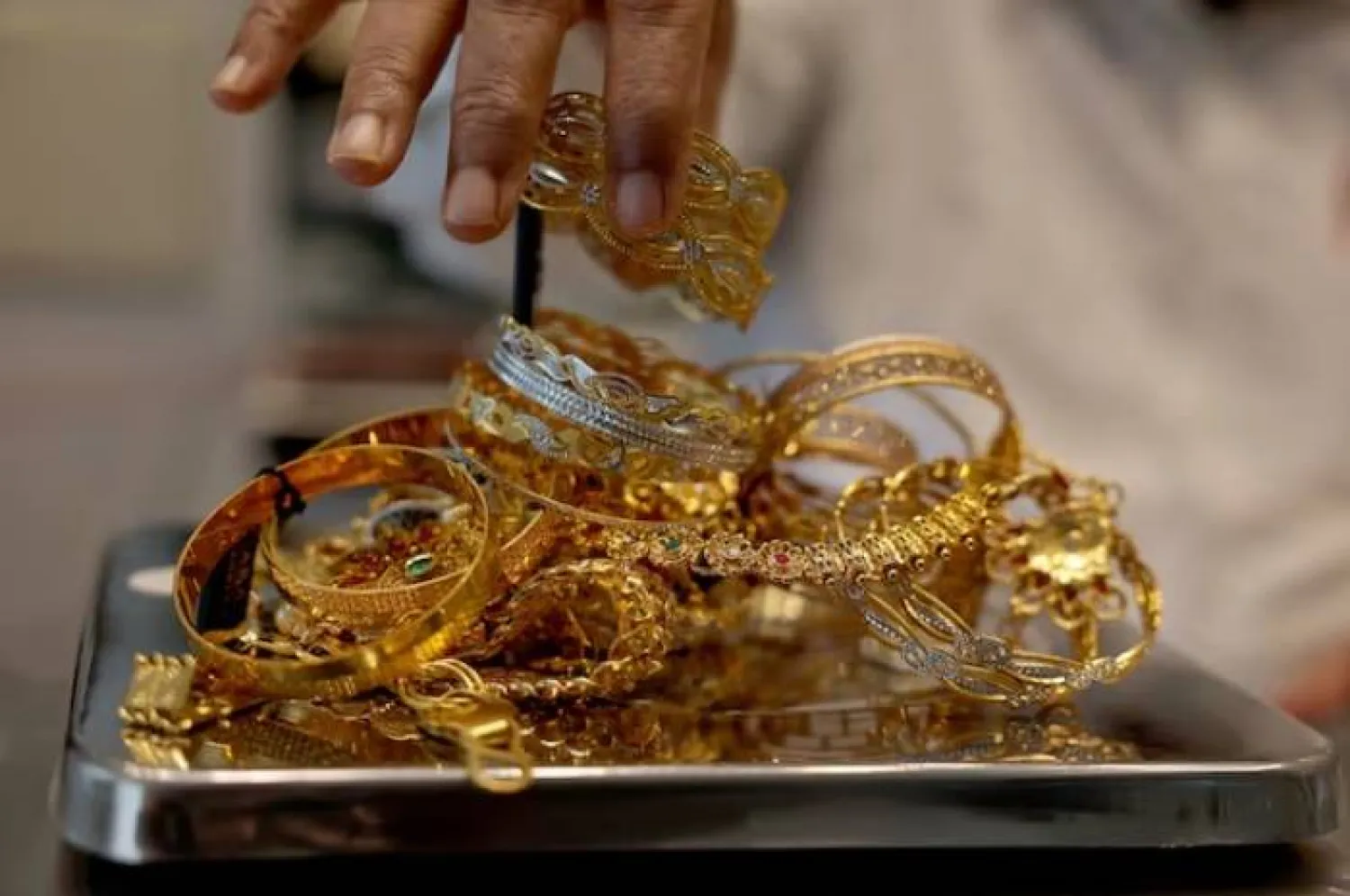 صائغ يزن أساور ذهبية داخل صالة عرض في أحمد آباد الهند (رويترز)