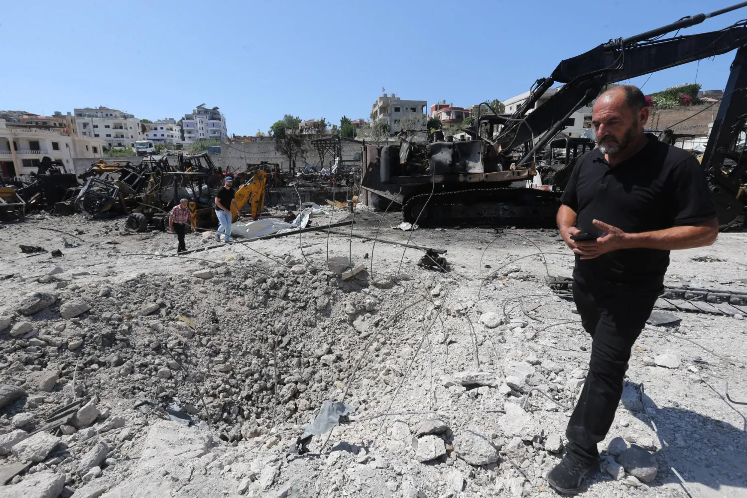 رجل يسير أمام حفرة بعد غارة جوية إسرائيلية على بلدة أنصارية في جنوب لبنان أمس