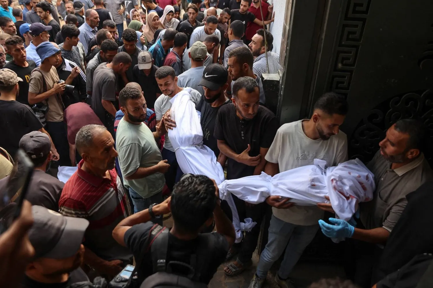 فلسطينيون يحملون جثث ضحايا الغارات الإسرائيلية على مدينة غزة (أ.ف.ب)