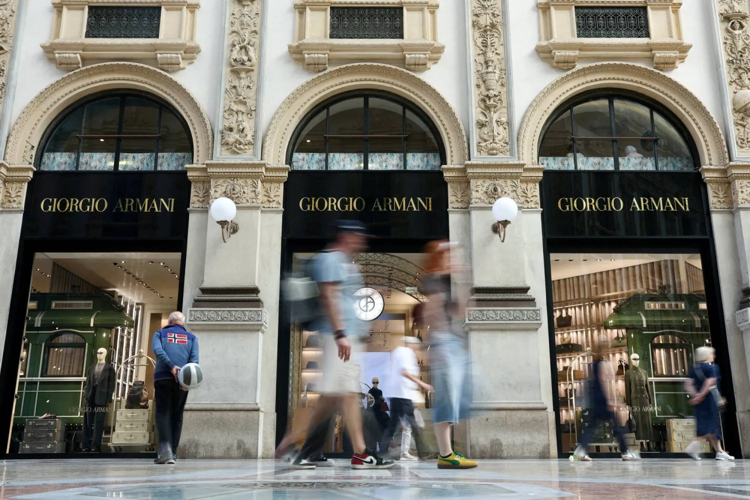 FILE PHOTO: People walk past a Giorgio Armani store in Galleria Vittorio Emanuele II, following Giorgio Armani's death at the age of 91, in Milan, Italy, September 5, 2025. REUTERS/Gonzalo Fuentes/File Photo