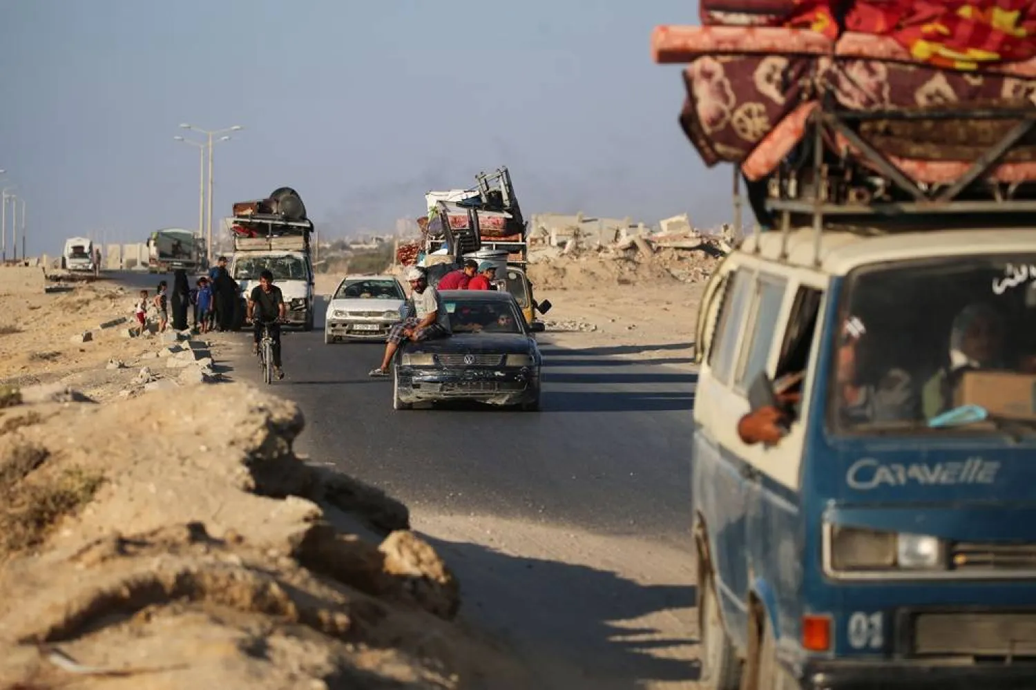 Palestinians fleeing south, ride vehicles with their belongings, along the coastal road near the Nuseirat camp in the central Gaza Strip, on August 5, 2025. (AFP)
