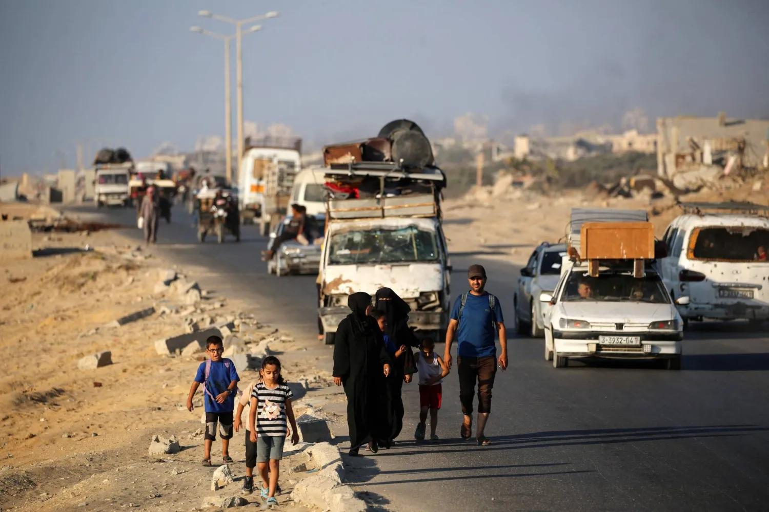 فلسطينيون فارّون جنوباً يستقلون سيارات محملة بأمتعتهم على طول الطريق الساحلي قرب مخيم النصيرات في وسط قطاع غزة (أ.ف.ب)