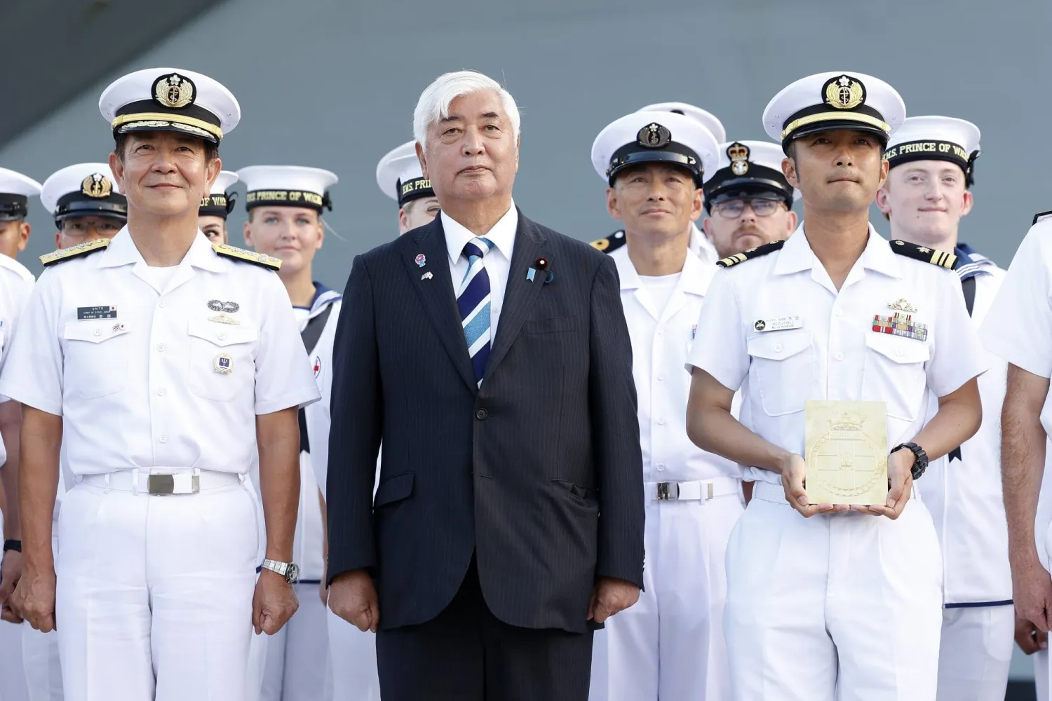 وزير الدفاع الياباني جين ناكاتاني (وسط) يحضر حفل ترحيب لحاملة طائرات بريطانية في طوكيو (إ.ب.أ)