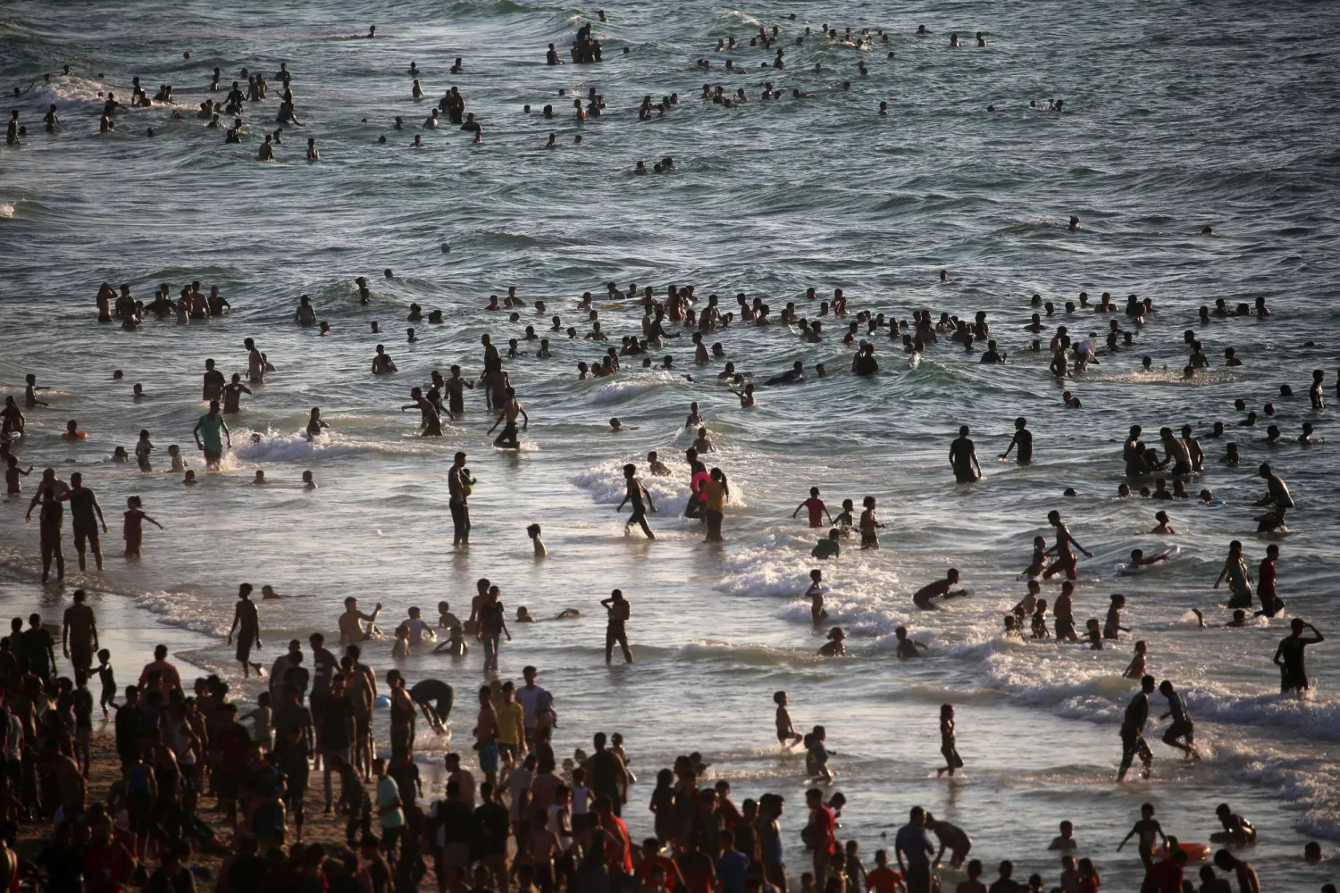 فلسطينيون يسبحون في البحر الأبيض المتوسط ​​للتبريد من حرارة الصيف قرب مخيم النصيرات للاجئين في وسط قطاع غزة يوم الجمعة (أ.ف.ب)
