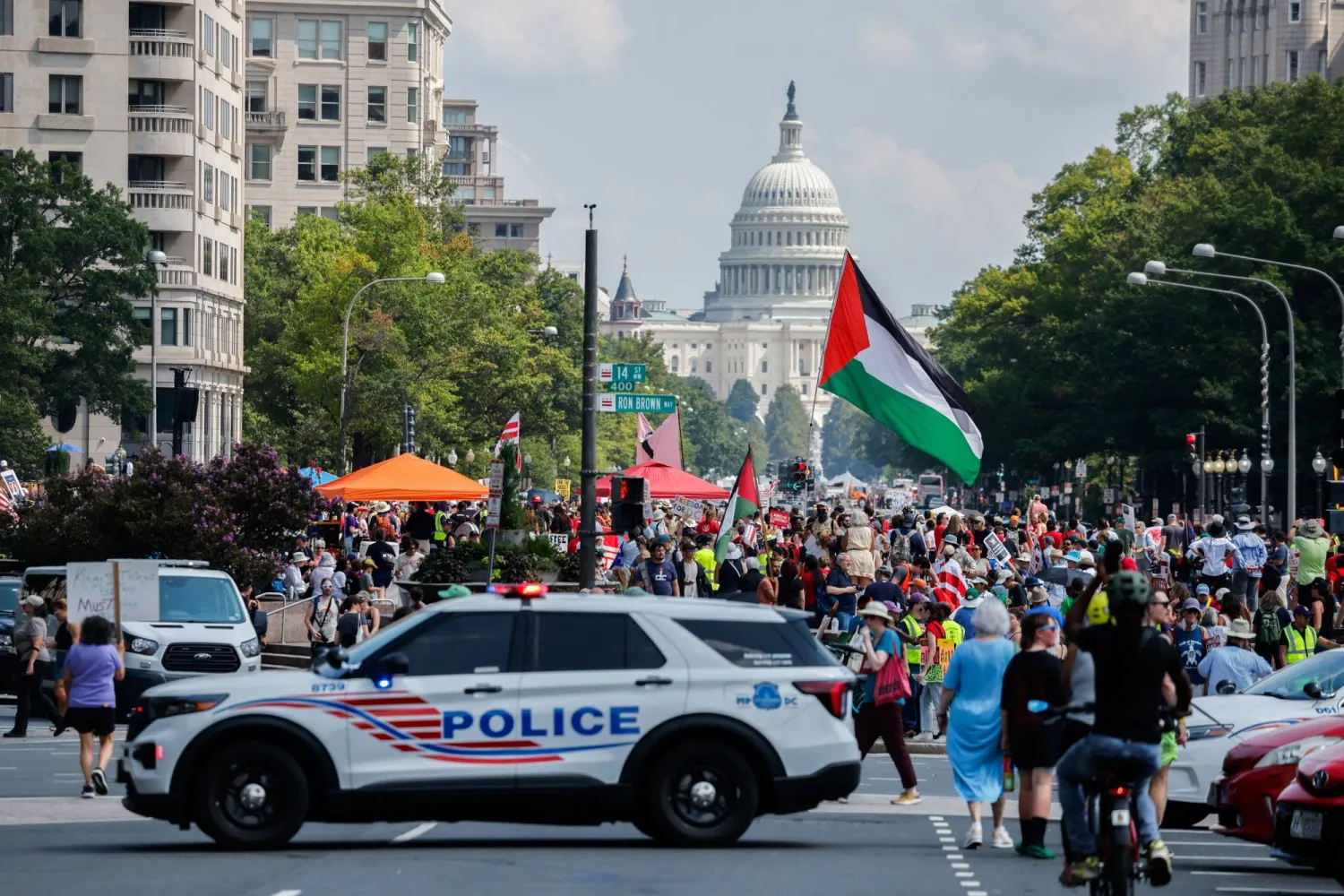 متظاهرون مناهضون لنشر الحرس الوطني في واشنطن بجوار سيارة شرطة قرب مبنى الكابيتول (رويترز)