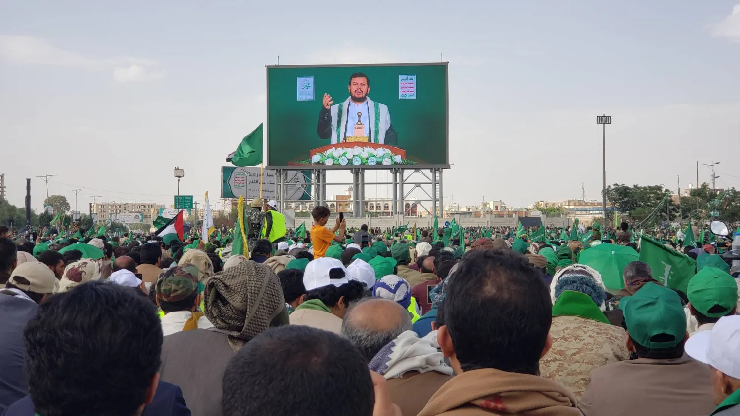 عناصر موالون للجماعة الحوثية في صنعاء يستمعون لخطبة زعيمهم عبر شاشة عملاقة (إ.ب.أ)